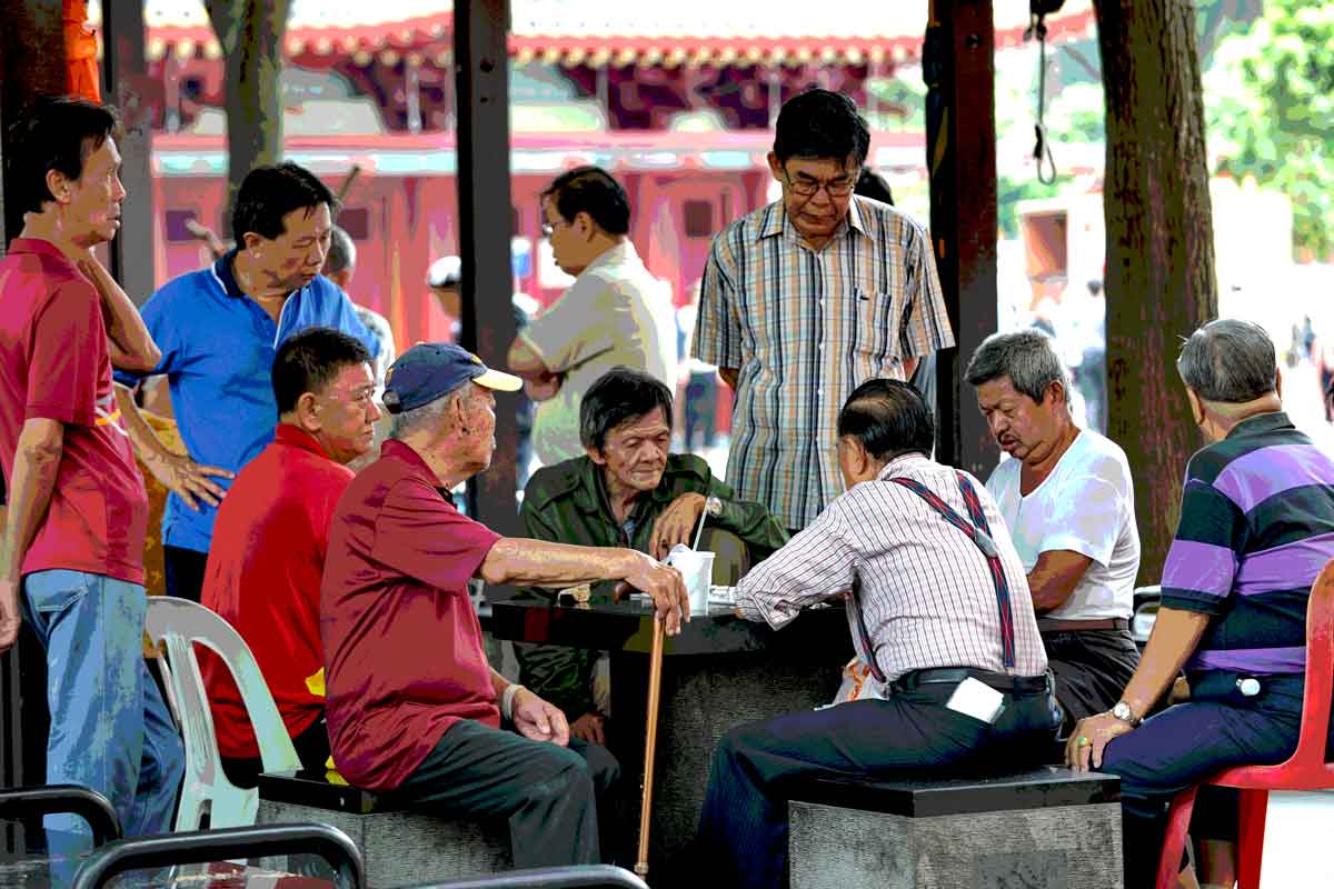 Personas mayores reunidas para jugar un juego de damas junto a su área de vivienda en Singapur