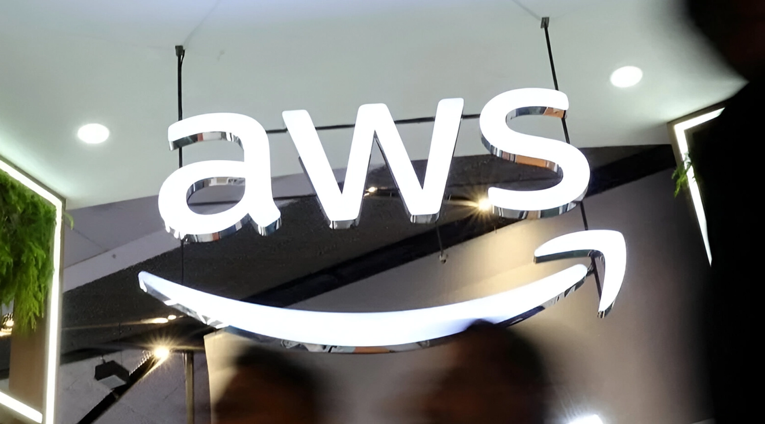Logotipo iluminado de Amazon Web Services (AWS) en un espacio corporativo moderno.