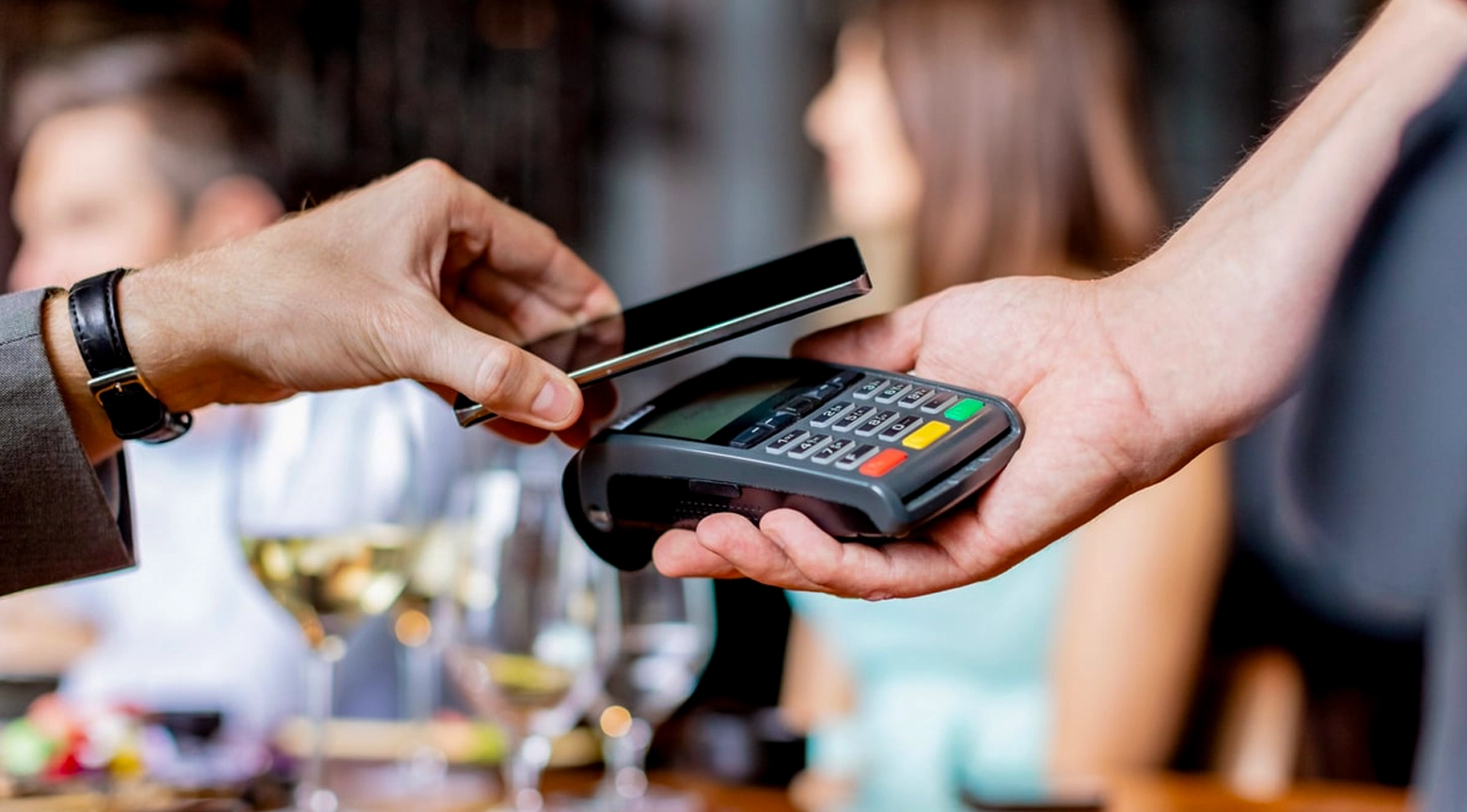 Persona realizando un pago sin contacto con su teléfono móvil sobre un datáfono en un restaurante.