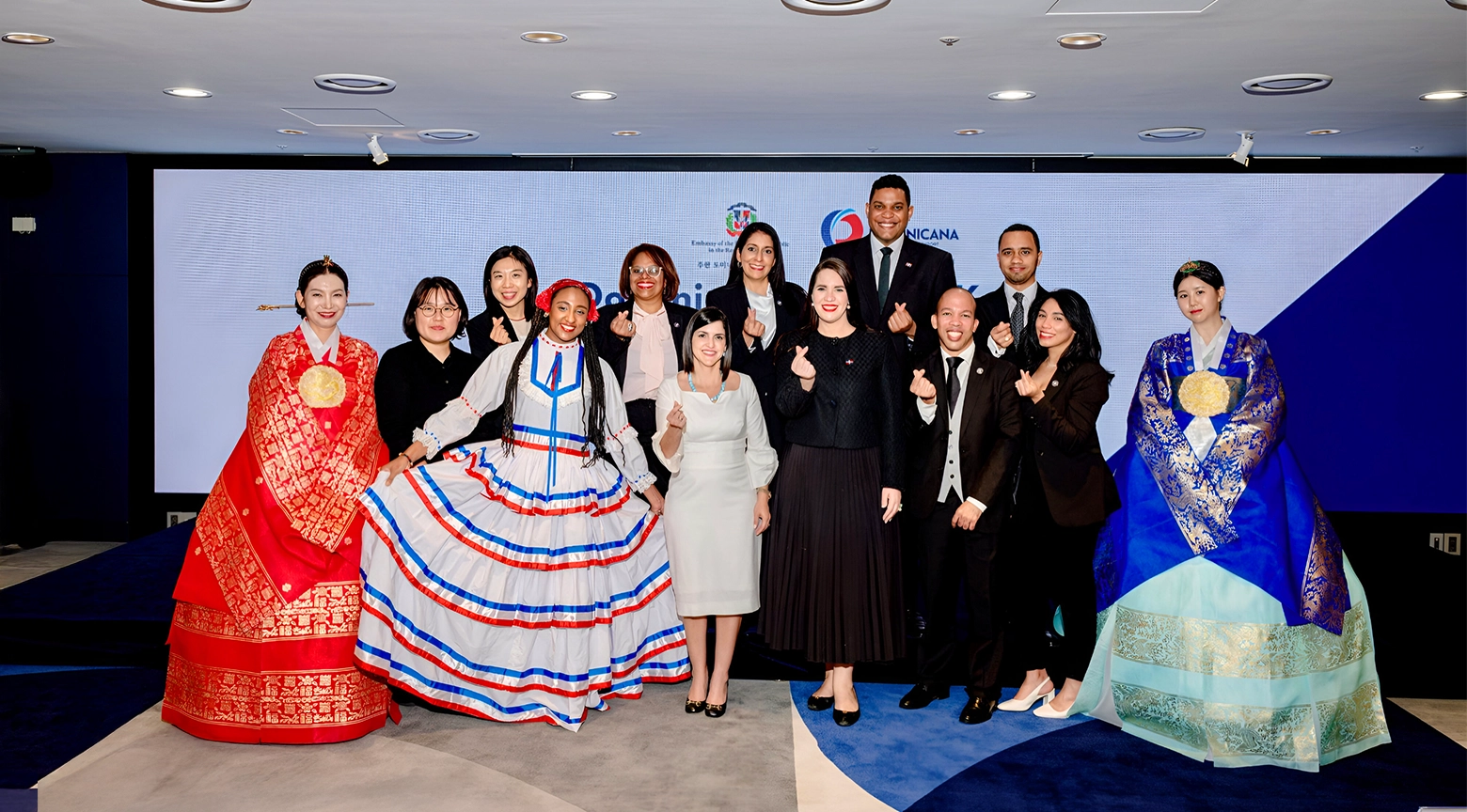 Grupo de representantes de la República Dominicana y Corea del Sur posan juntos durante un evento cultural, luciendo trajes tradicionales de ambos países.