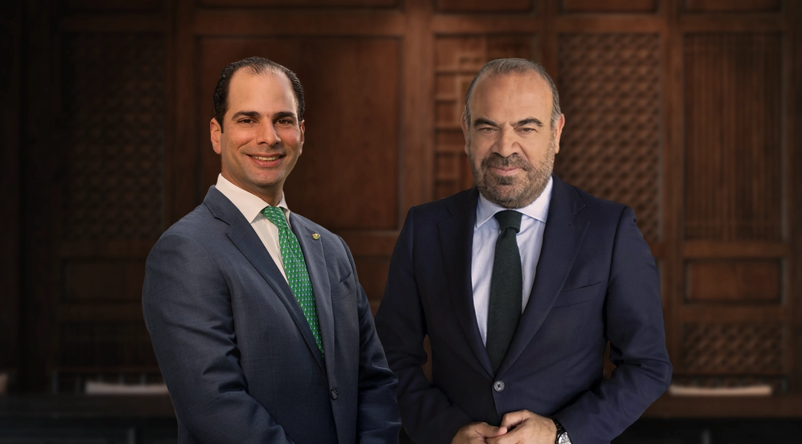 Dos empresarios posan con traje formal frente a un fondo de madera, representando una alianza en el sector turístico.