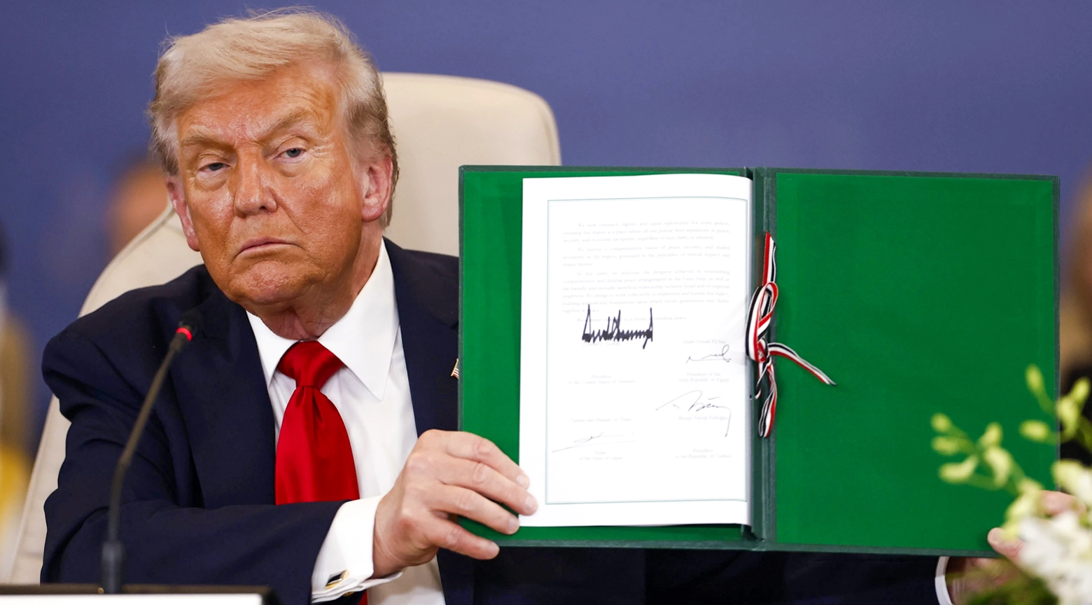 Donald Trump sostiene un documento firmado durante la ceremonia que marca el fin de la guerra en Gaza.