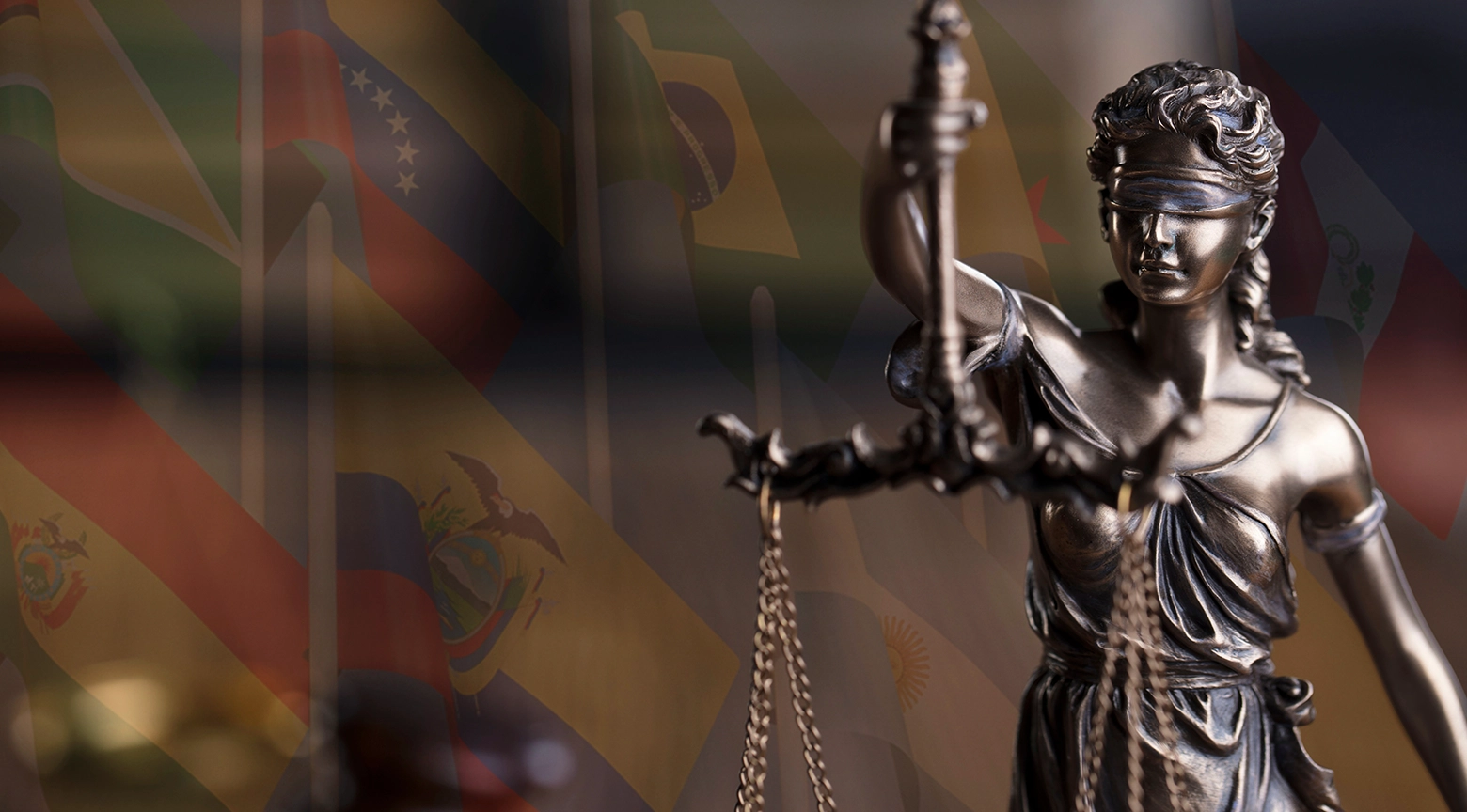 Estatua de la justicia con fondo de banderas latinoamericanas.