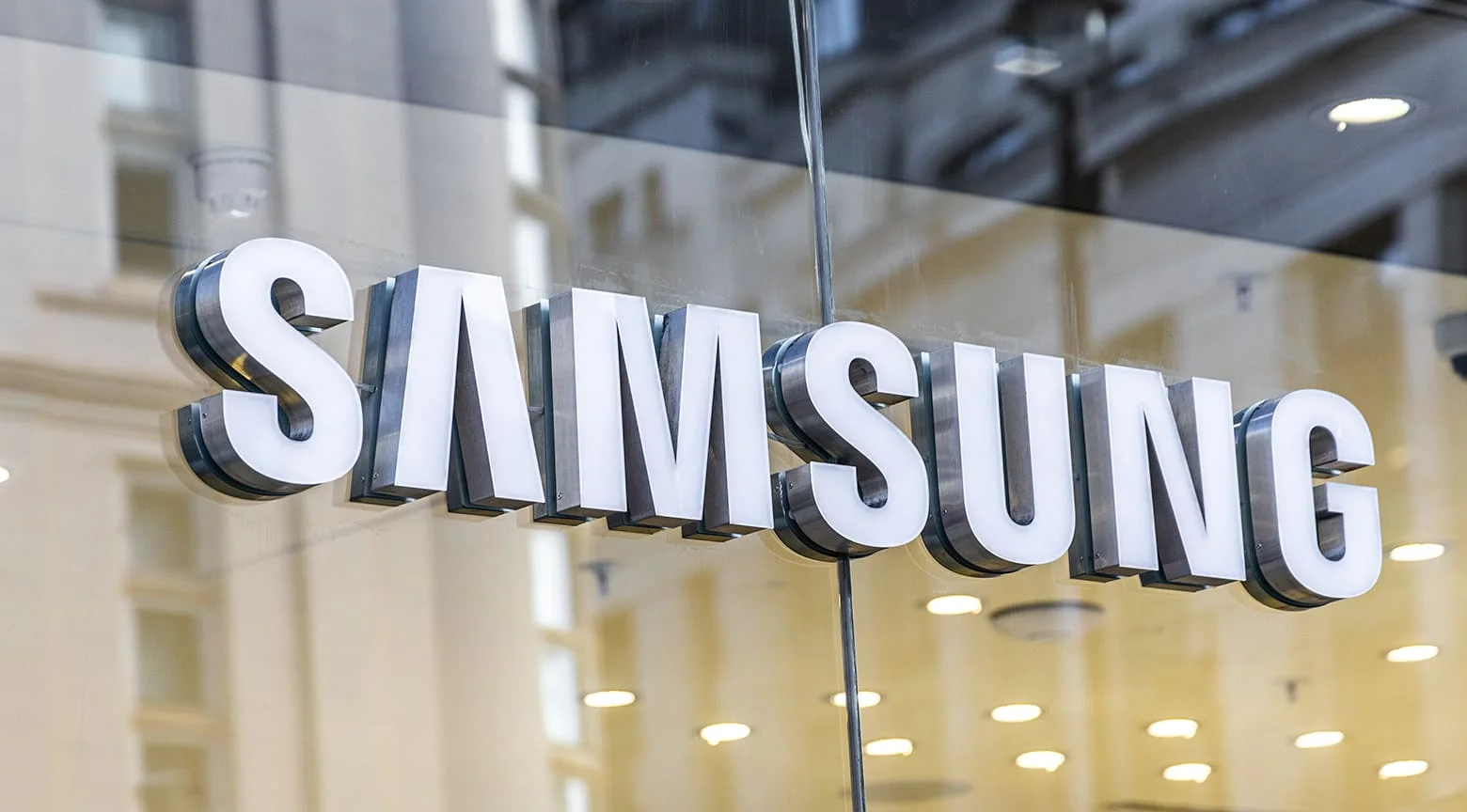 Logo tridimensional de Samsung en la fachada de una tienda con fondo urbano.