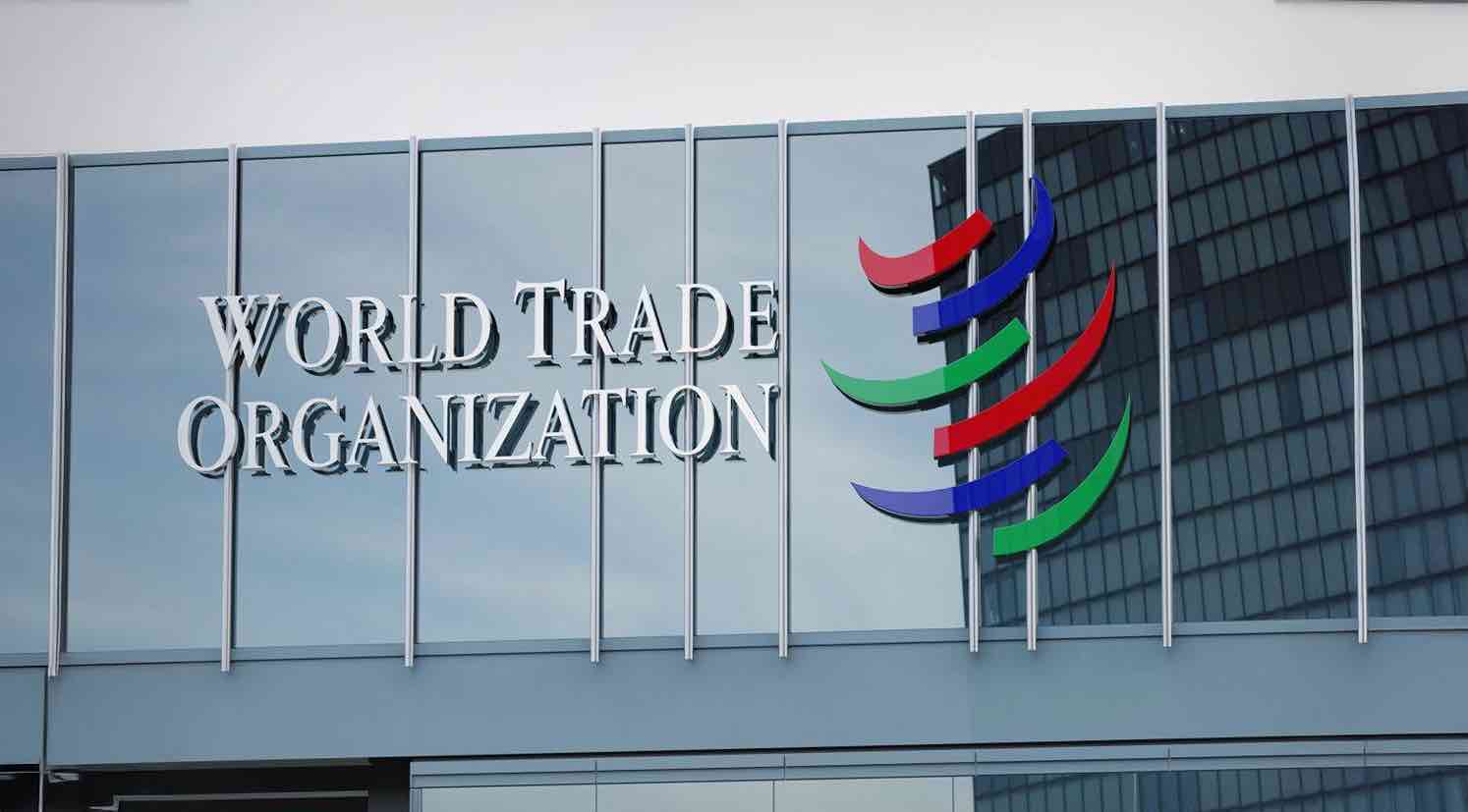 Fachada de la Organización Mundial del Comercio con su logotipo multicolor sobre un edificio de vidrio.