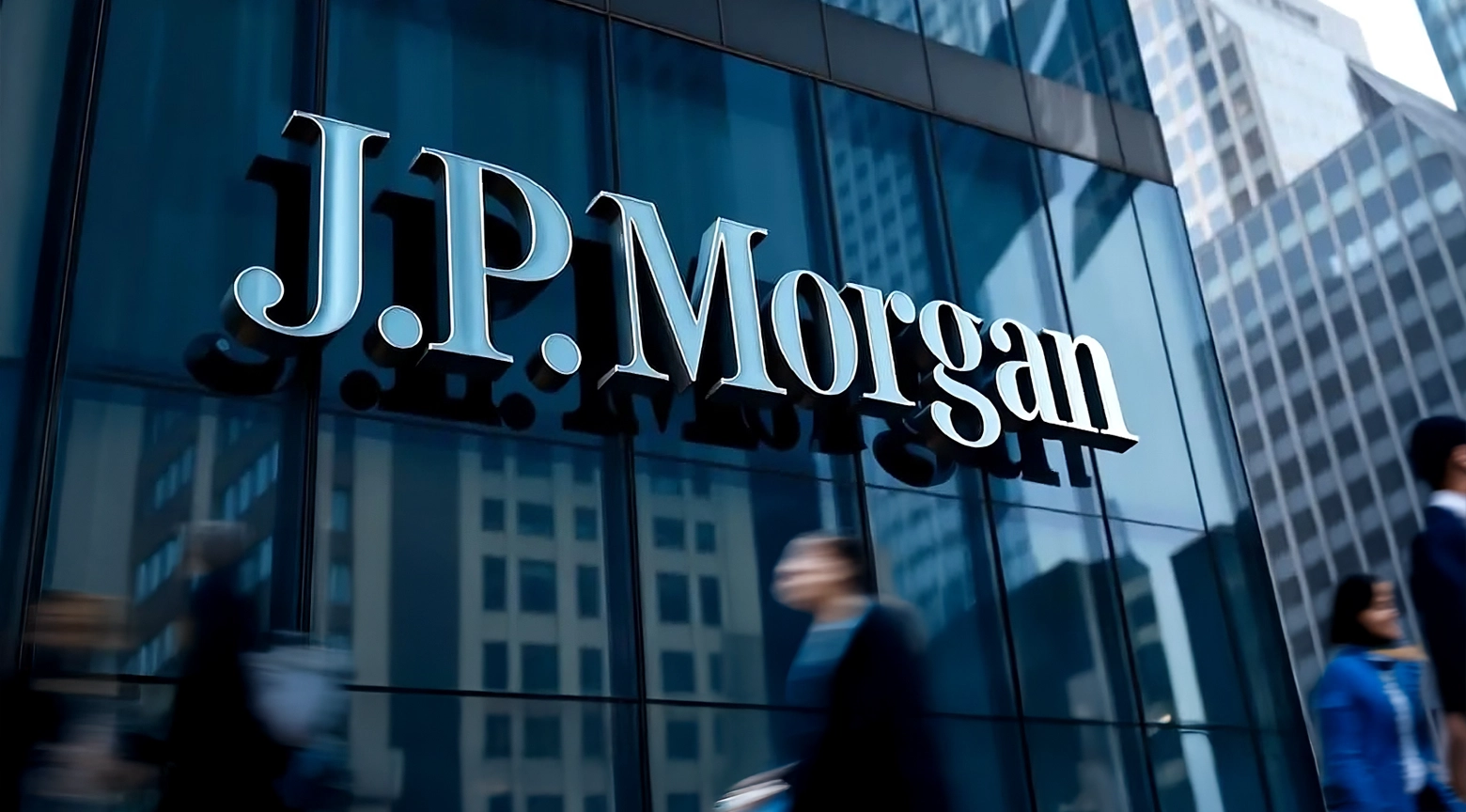 Fachada acristalada de un edificio corporativo con el logotipo de J.P. Morgan reflejando los rascacielos de la ciudad.