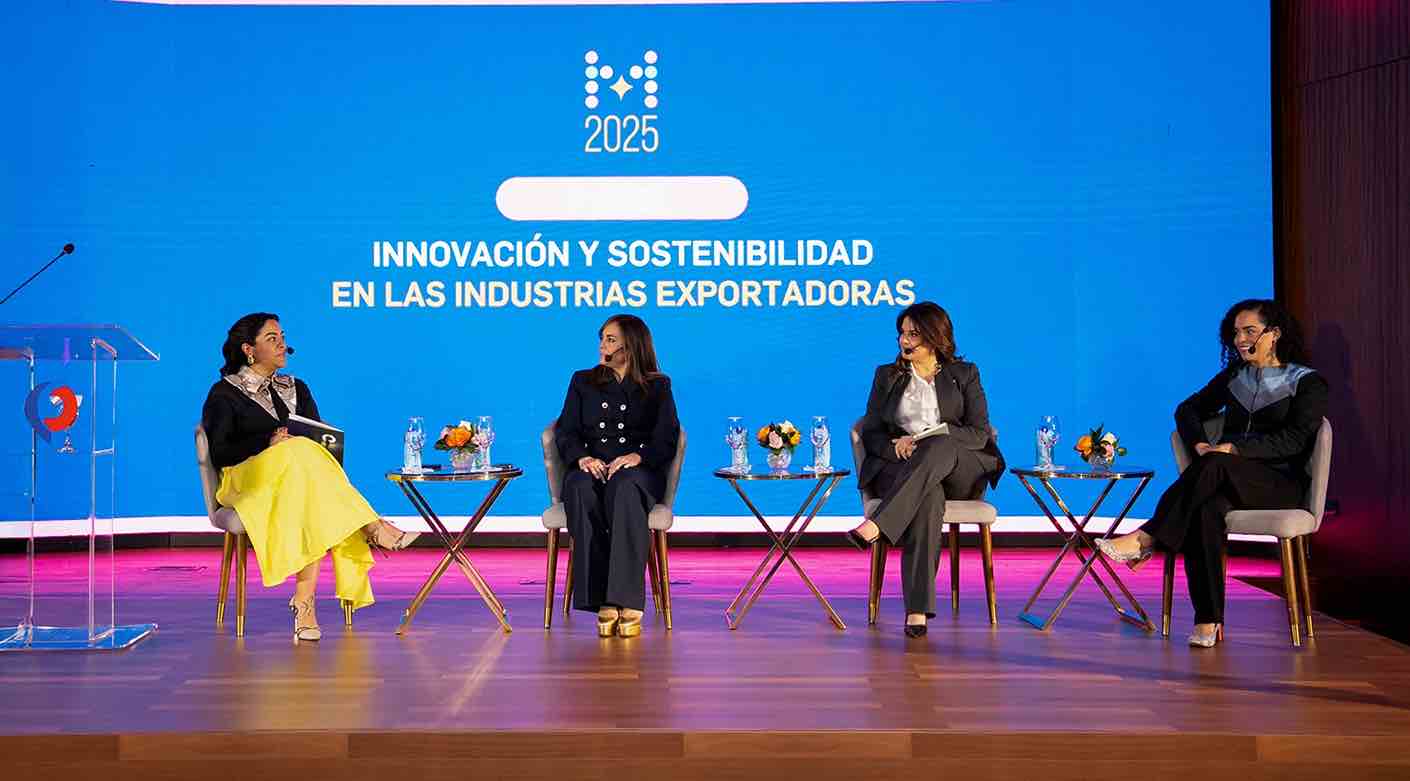Panel de cuatro mujeres conversando en un escenario durante un evento sobre innovación y sostenibilidad en las industrias exportadoras, con una gran pantalla azul de fondo.