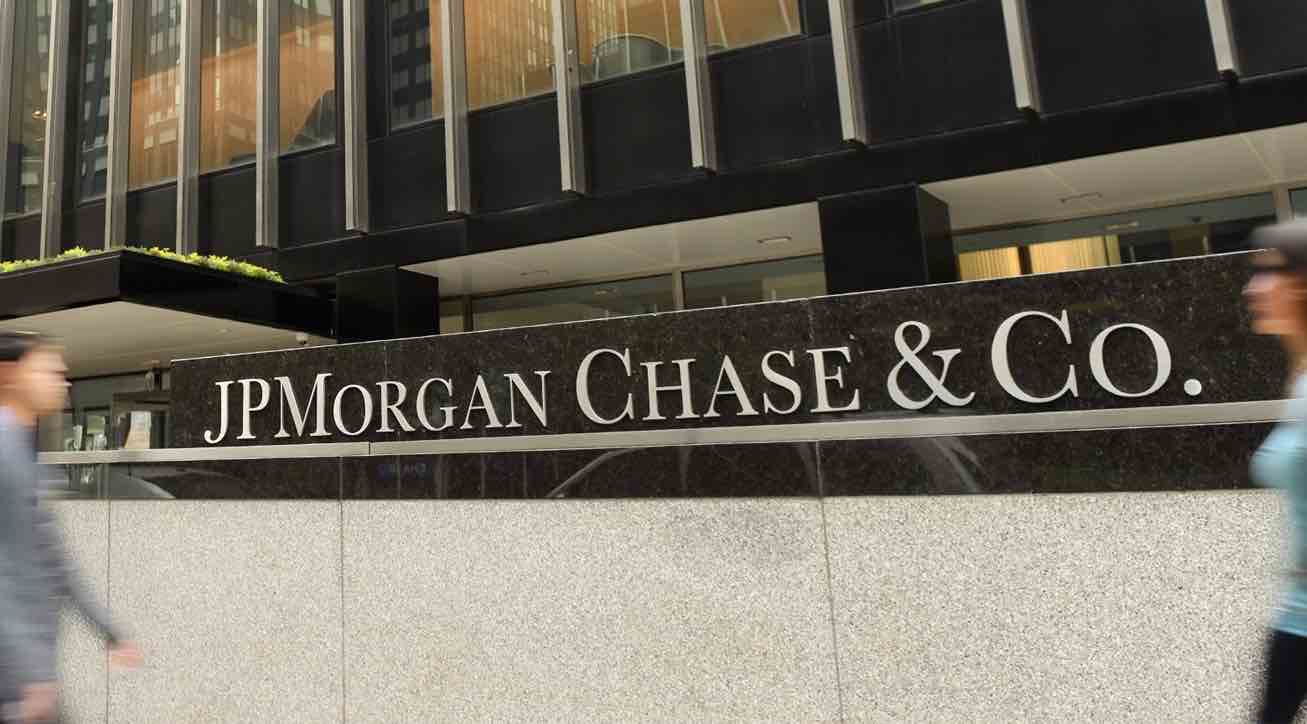 Fachada del edificio de JPMorgan Chase & Co. con su logotipo en una placa de piedra, mientras personas caminan frente a la entrada.