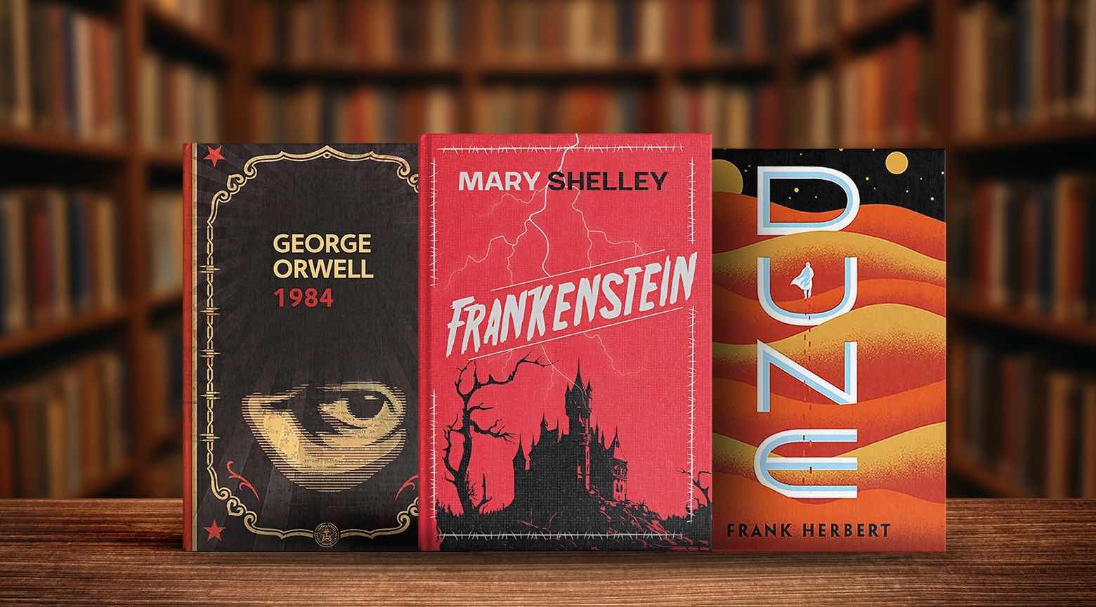 Portadas de los libros 1984, Frankenstein y Dune expuestas sobre una mesa en una biblioteca.