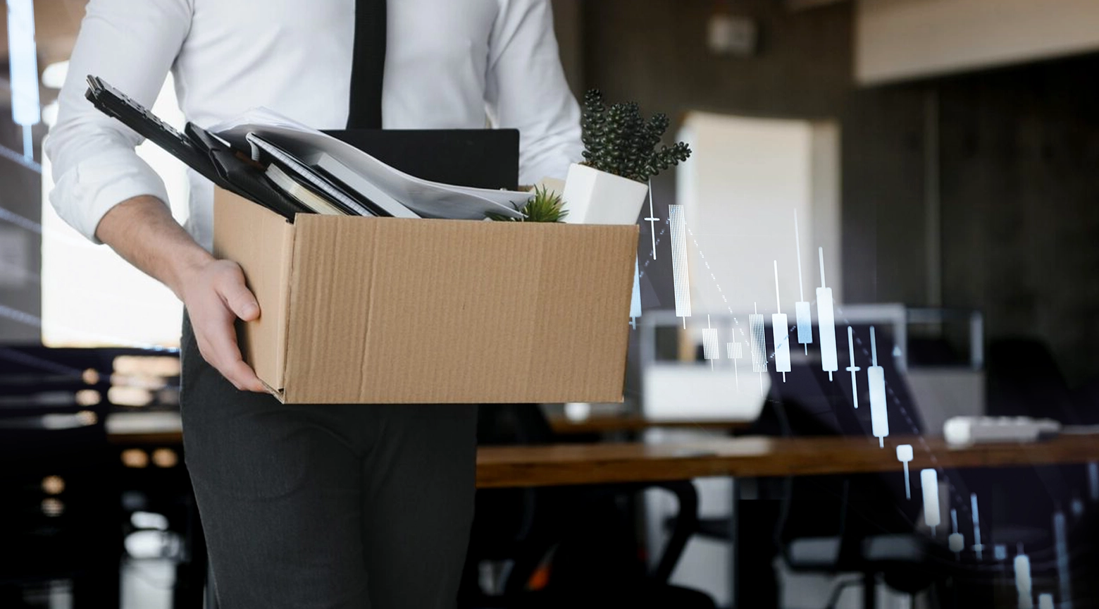 Persona vestida formalmente sostiene una caja con objetos personales en una oficina, simbolizando despidos laborales.