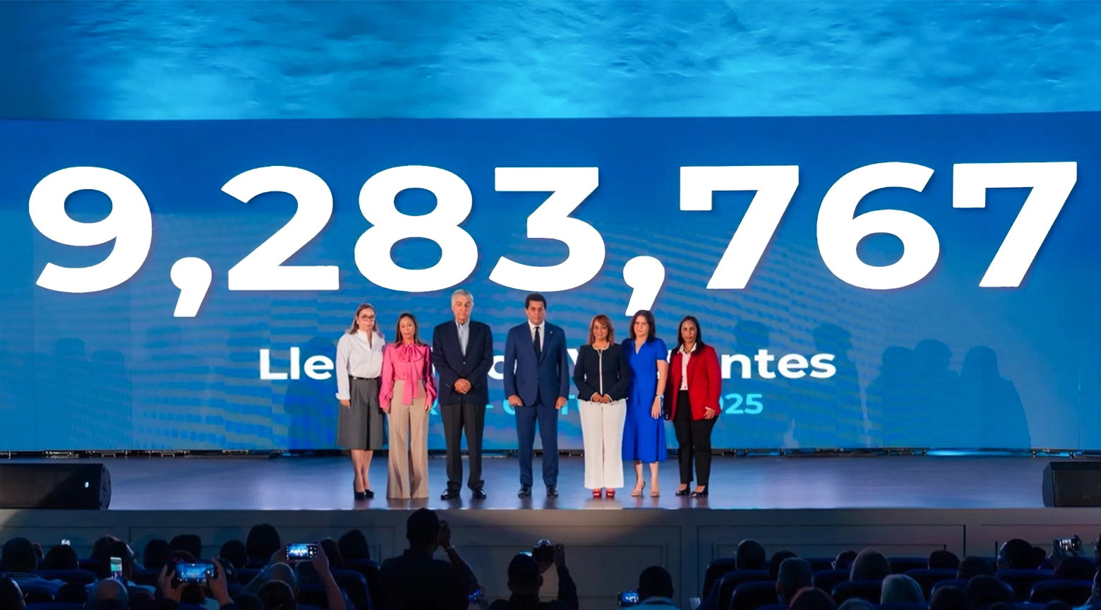 Un grupo de autoridades y representantes del sector turístico posa en un escenario frente a una pantalla gigante que muestra la cifra “9,283,767 llegadas”, durante un evento oficial en República Dominicana.