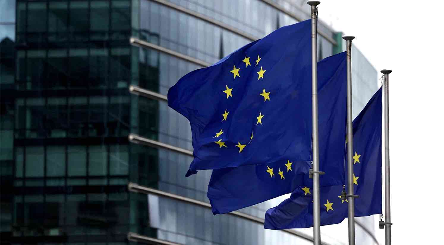 Banderas de la Unión Europea ondeando frente a un edificio institucional en Bruselas.
