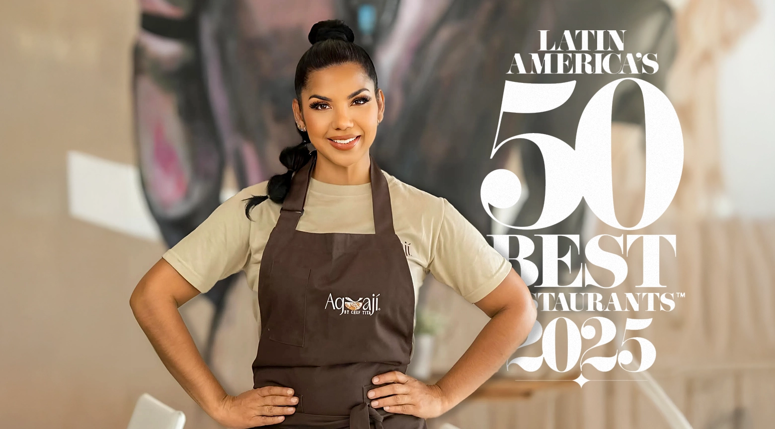 Chef Tita posa con su delantal frente al logo de Latin America’s 50 Best Restaurants 2025.