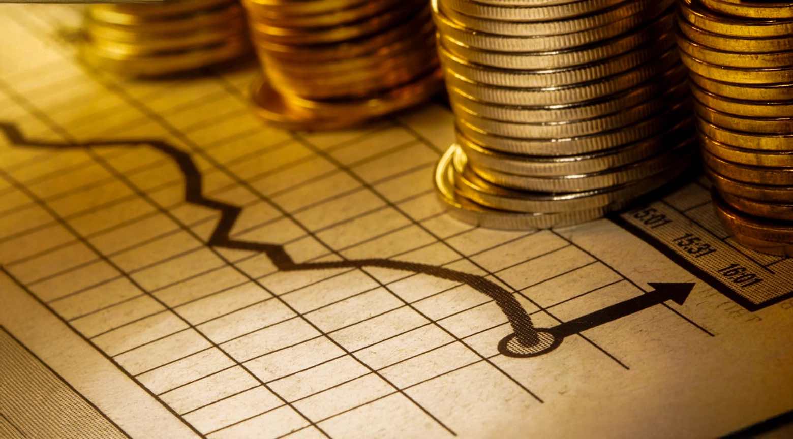 Gráfico financiero con monedas apiladas y una flecha ascendente que representa el aumento de las tasas de interés en países de América Latina.