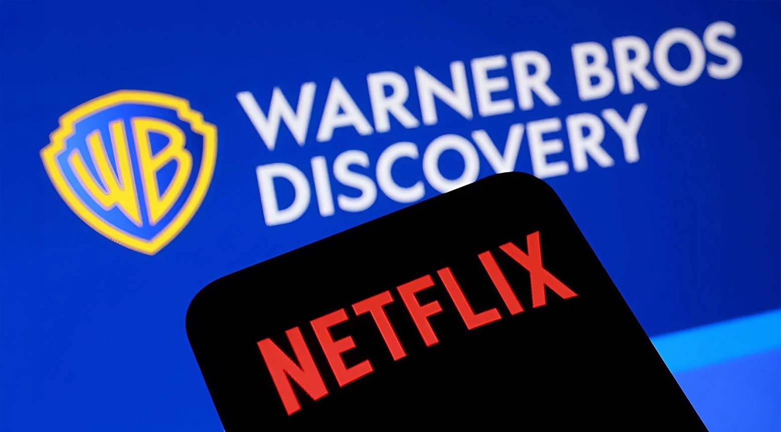 Logos de Netflix y Warner Bros. Discovery, con el primero en una pantalla de móvil en primer plano y el segundo en un fondo azul.