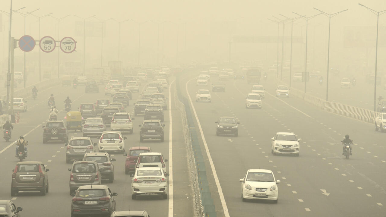 Tráfico vehicular intenso en una autopista urbana cubierta por una densa nube de smog que reduce la visibilidad.