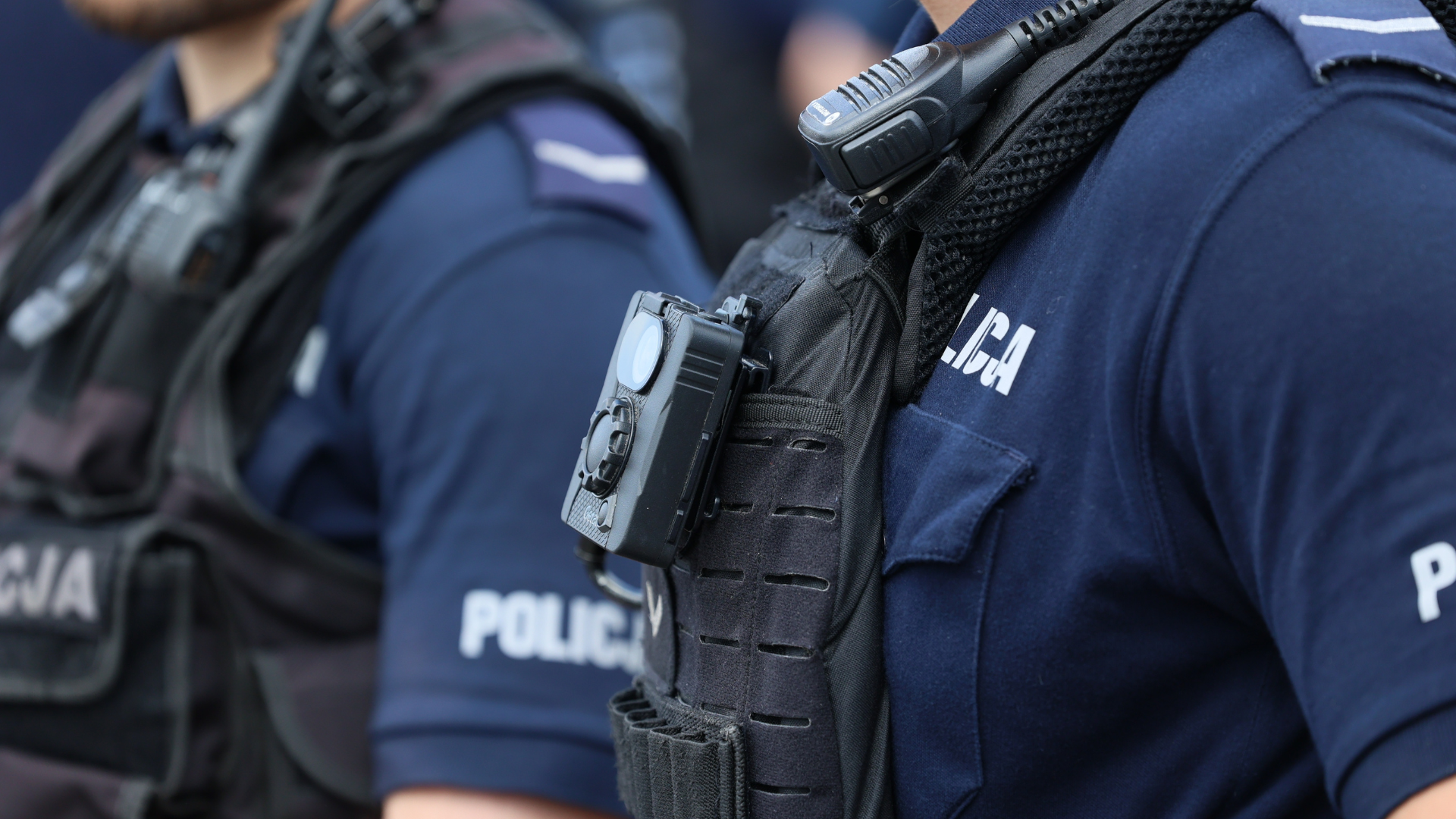 Detalle de agentes de policía con cámaras corporales y radios integrados en sus chalecos tácticos.