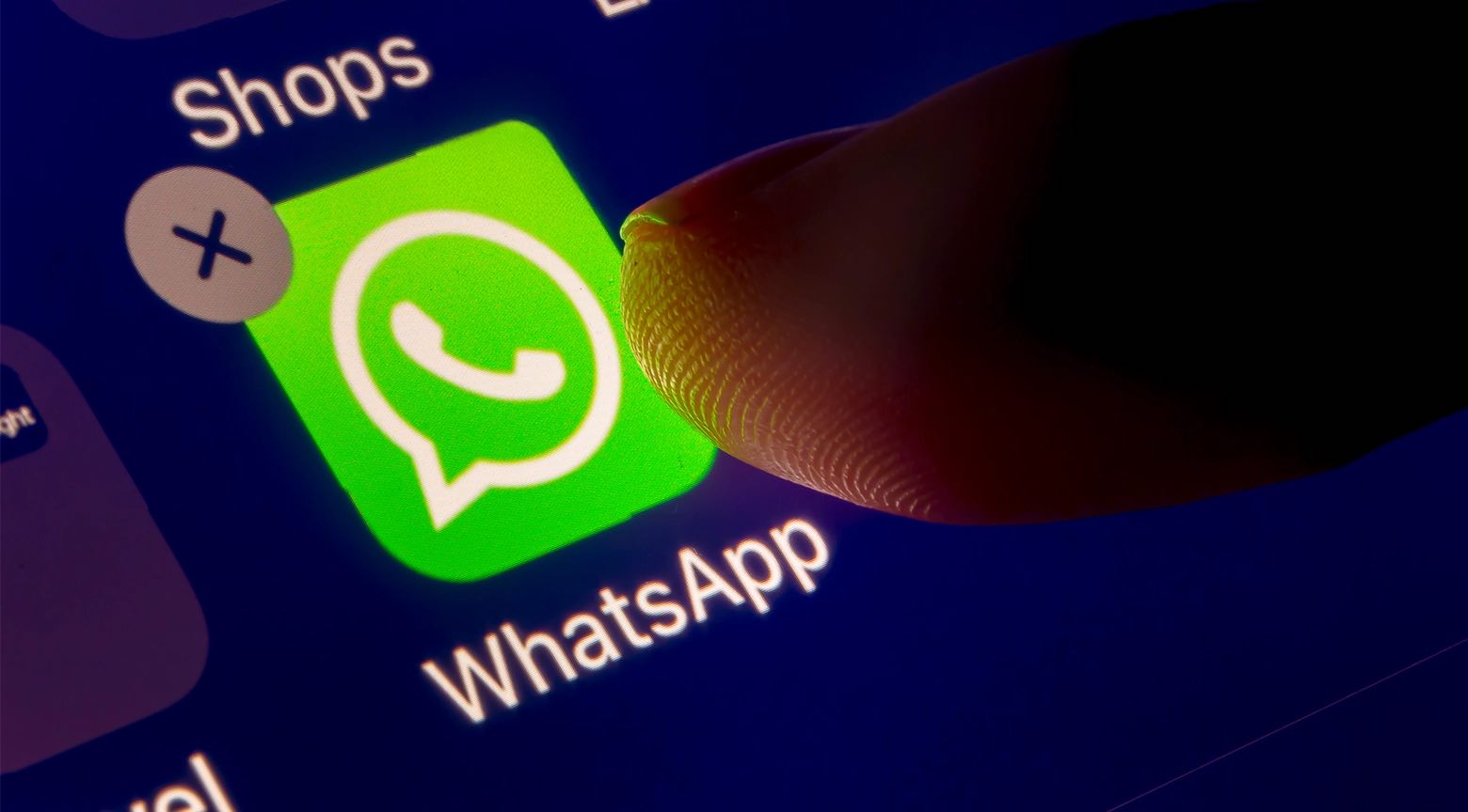 Dedo presionando el ícono de WhatsApp en la pantalla de un teléfono inteligente.