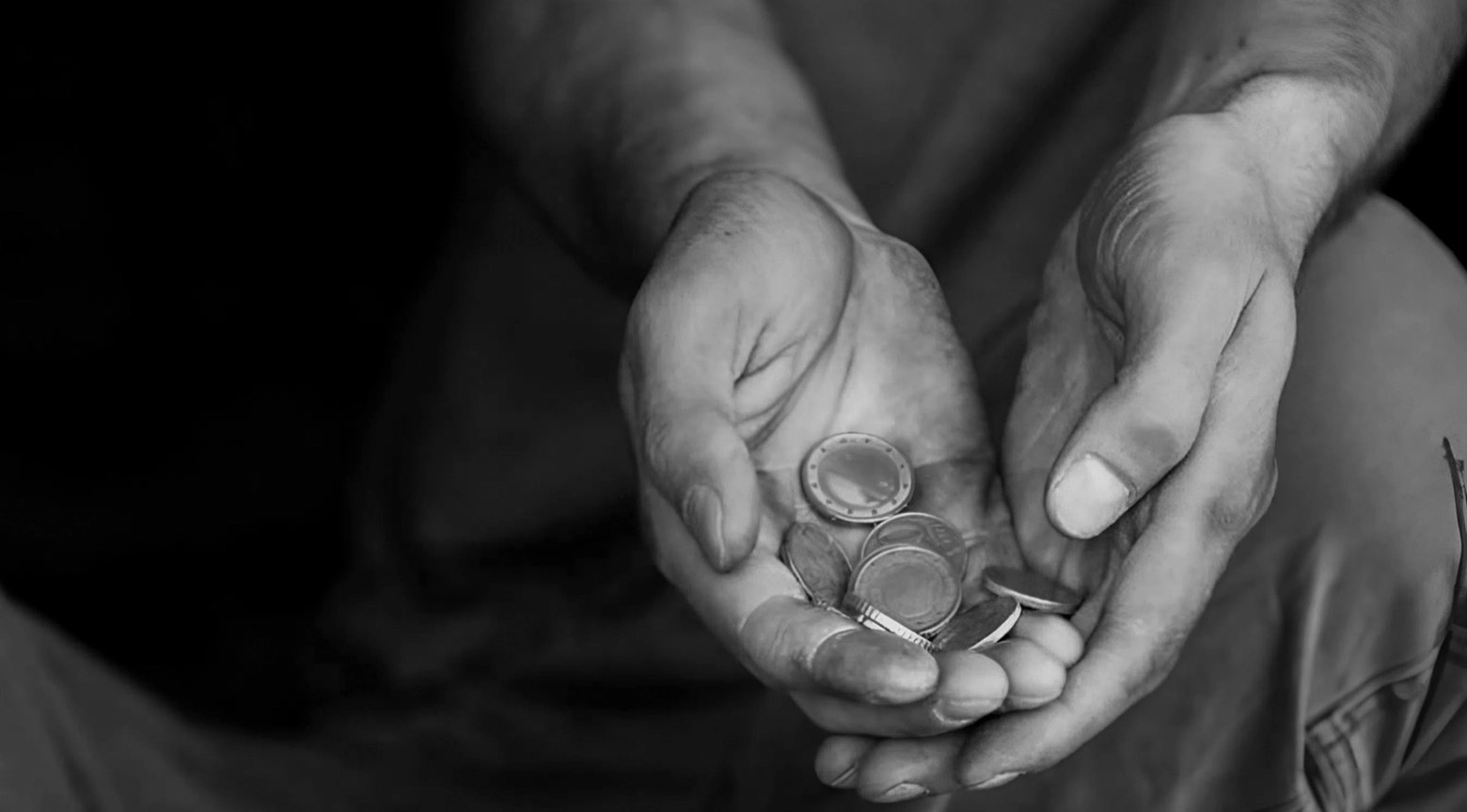 Manos de una persona sosteniendo unas pocas monedas, símbolo de pobreza y vulnerabilidad económica.