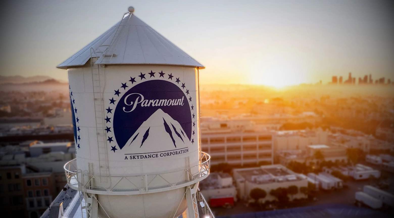 Torre de agua de Paramount Pictures con su logotipo, al atardecer, sobre el paisaje urbano de Hollywood.