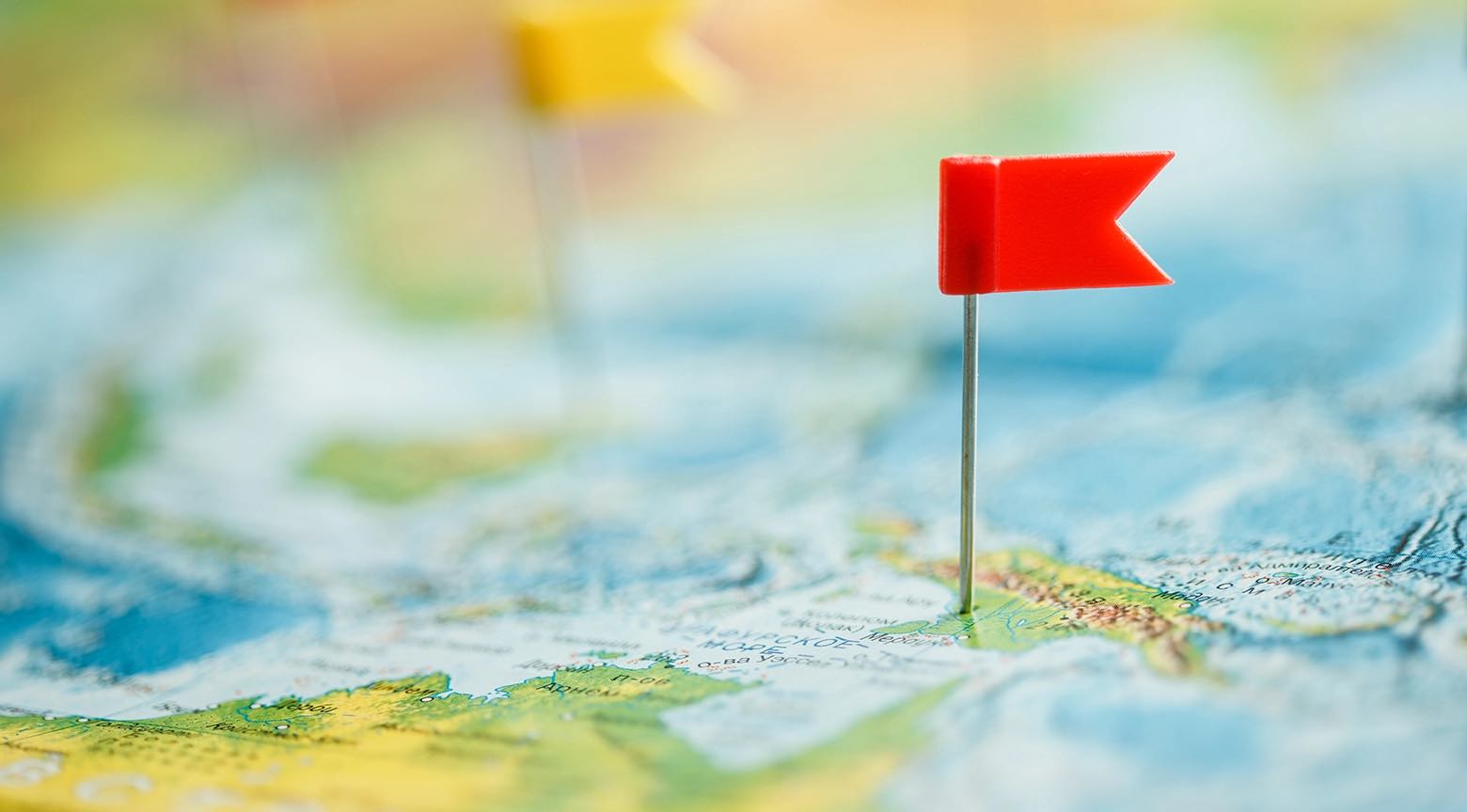 Bandera roja marcando un punto específico en un mapa del mundo, simbolizando la ubicación de un país dentro de un ranking global de influencia.