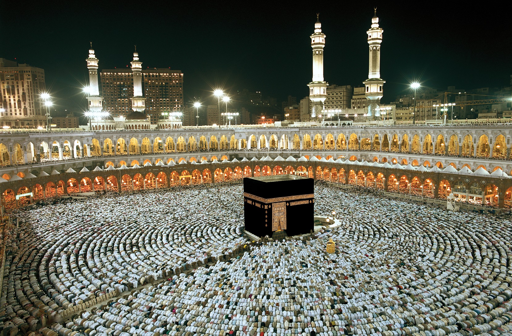 Vista nocturna de la Kaaba en la Gran Mezquita de La Meca, rodeada por miles de fieles reunidos para la oración.