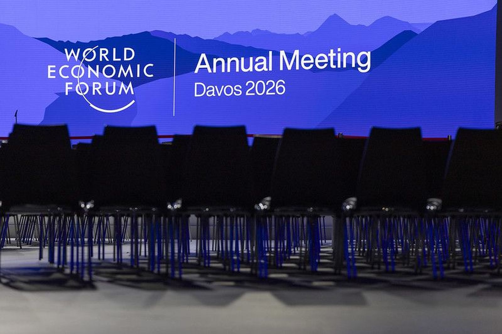 Escenario del Foro Económico Mundial con pantalla que anuncia la Reunión Anual de Davos 2026 y filas de sillas vacías al frente.