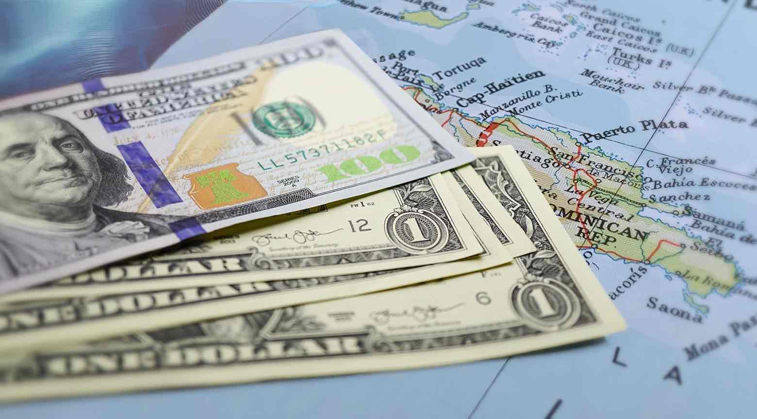 Billetes de dólares estadounidenses colocados sobre un mapa de la República Dominicana, con enfoque en la región norte del país.