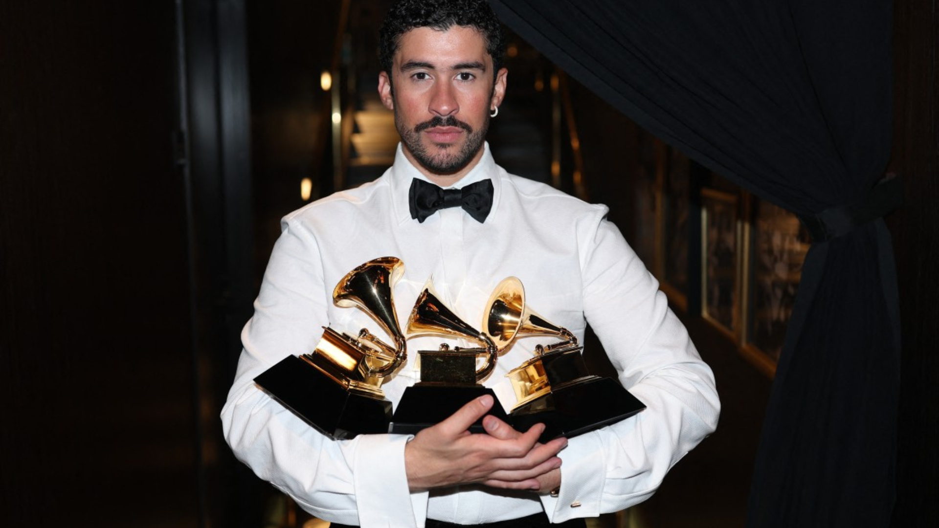 Bad Bunny sostiene varios premios Grammy tras la ceremonia, en una imagen difundida en el marco de su histórica participación en los premios.