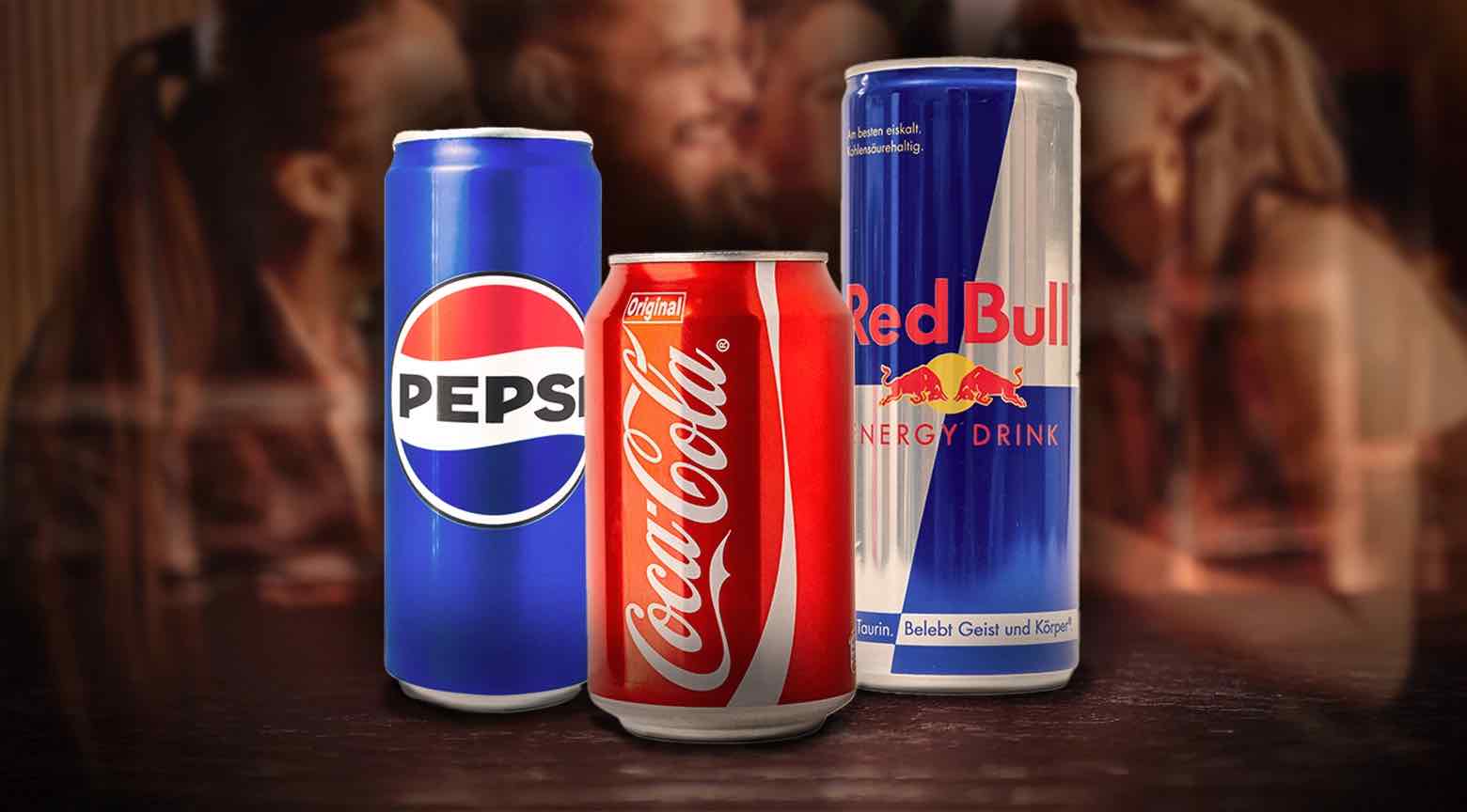 Latas de Pepsi, Coca-Cola y Red Bull sobre una mesa.