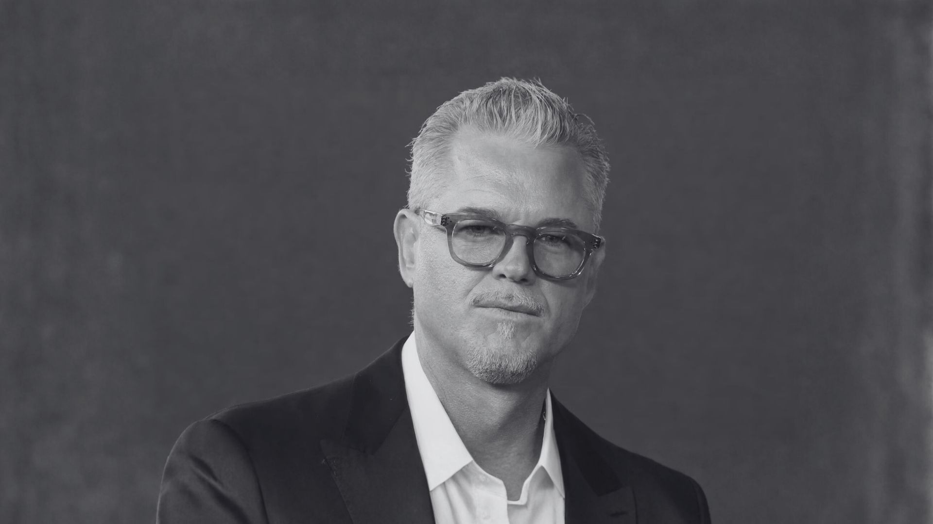Retrato en blanco y negro de un hombre con gafas y cabello corto canoso.