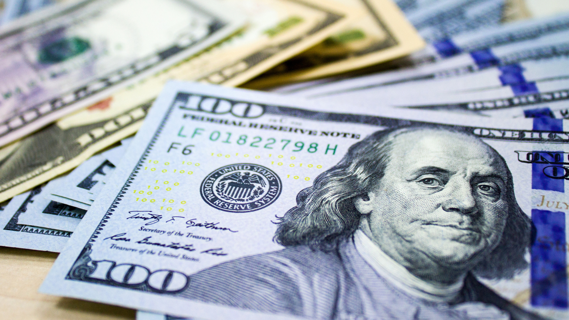 Billetes de 100 dólares estadounidenses apilados y en primer plano con el rostro de Benjamin Franklin.
