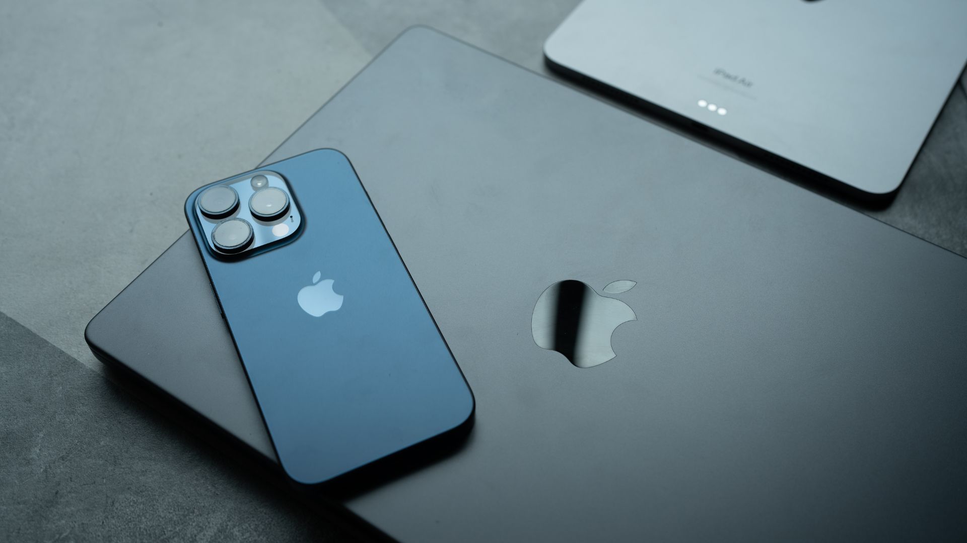 iPhone azul colocado sobre una MacBook con logotipo de Apple visible.