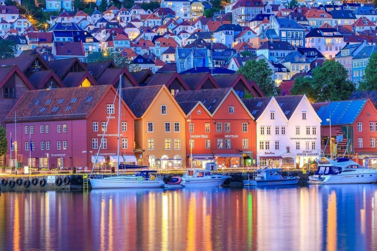 Vista nocturna del puerto de Bergen, Noruega, con casas coloridas reflejándose en el agua.
