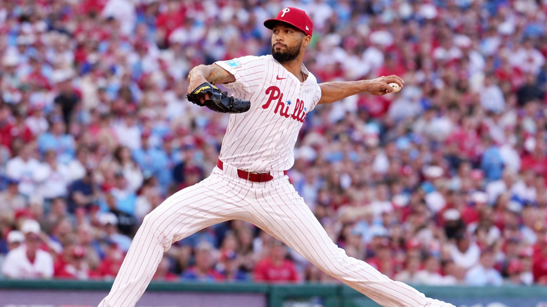 Lanzador de los Philadelphia Phillies en pleno movimiento de lanzamiento durante un partido, con el estadio lleno de fondo.