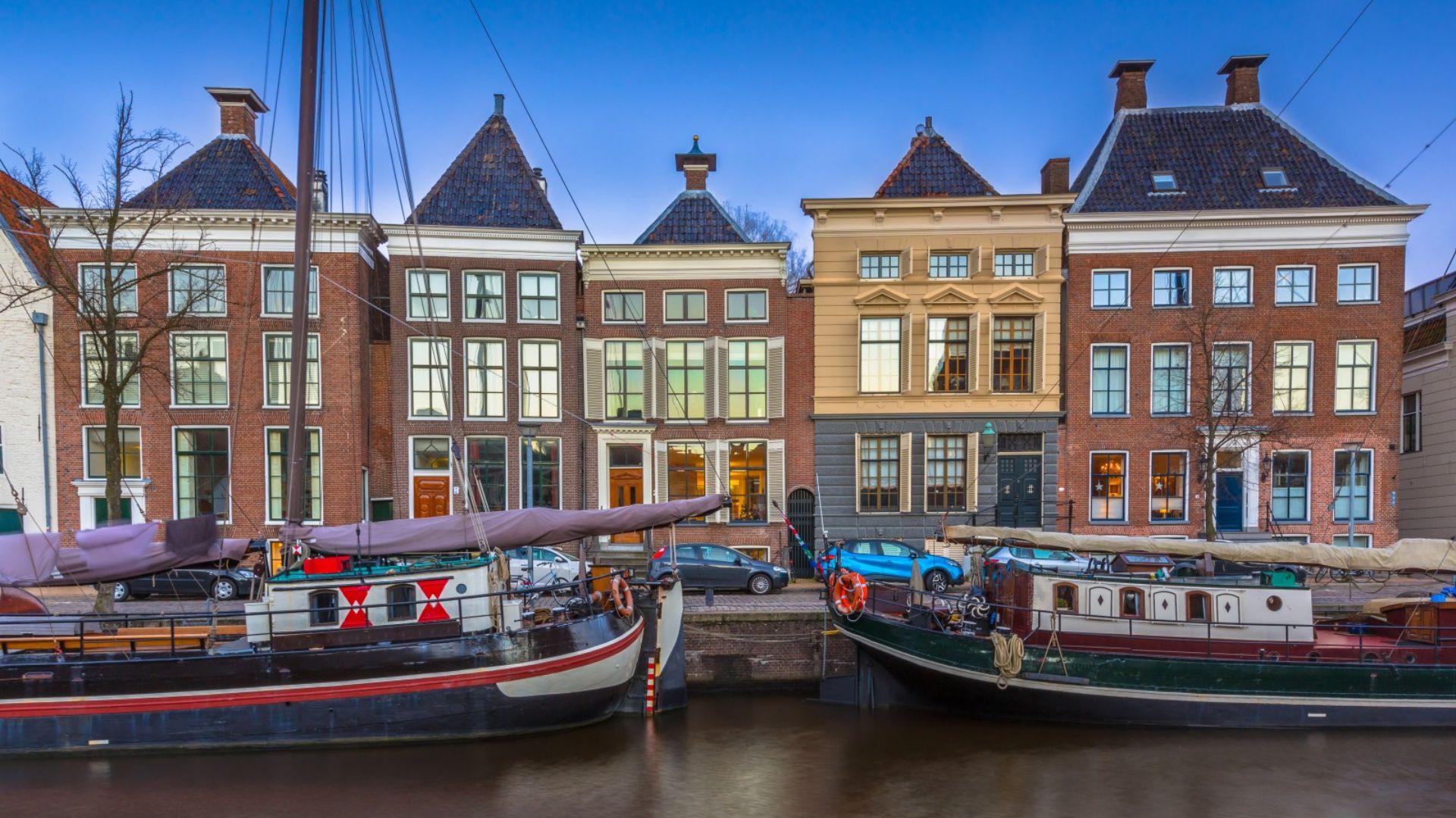 Vista de casas tradicionales a lo largo de un canal en una ciudad europea, con barcos atracados al borde.