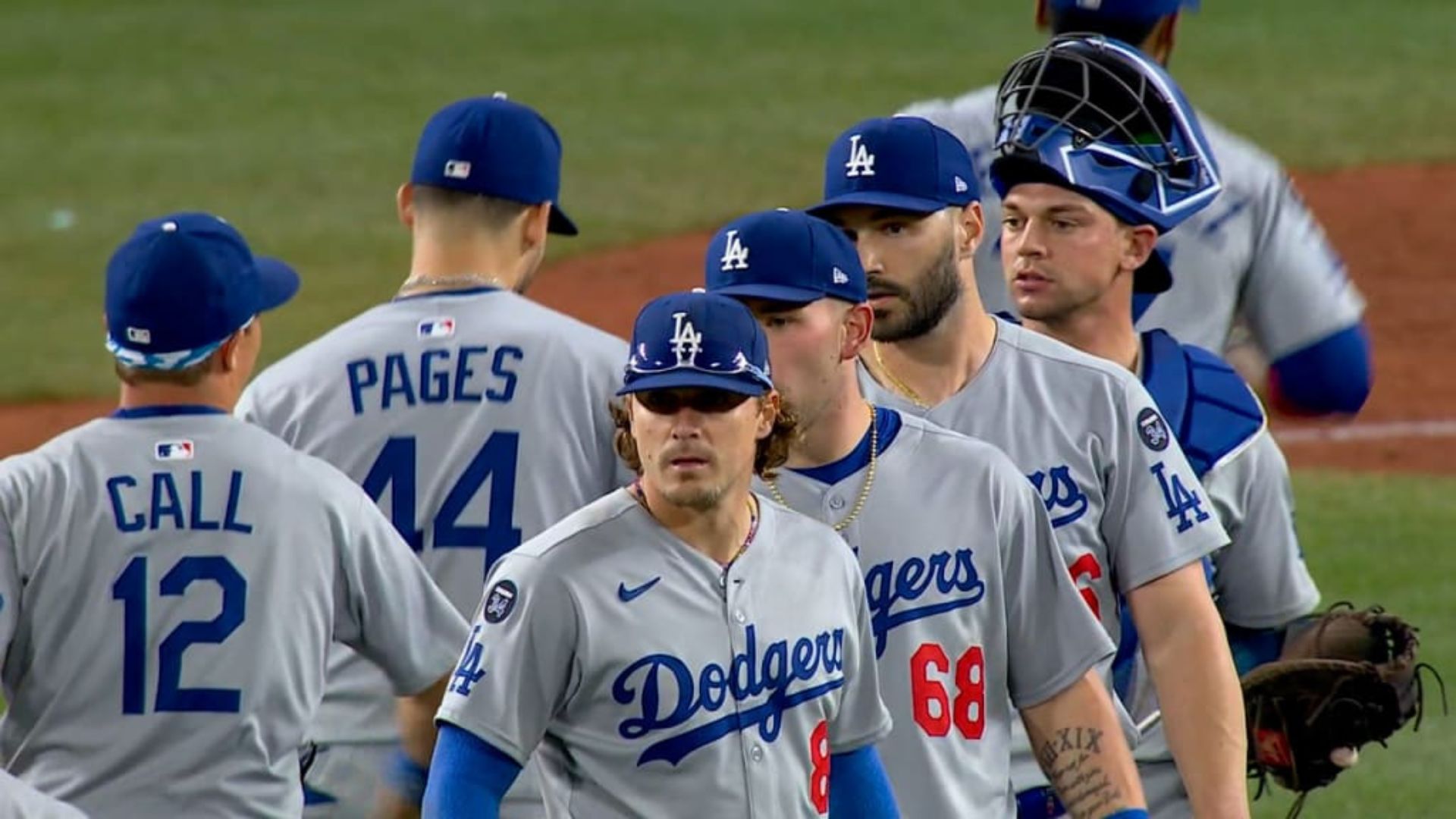 Jugadores de Los Angeles Dodgers saludando después de un partido, usando su uniforme gris con el logo del equipo.
