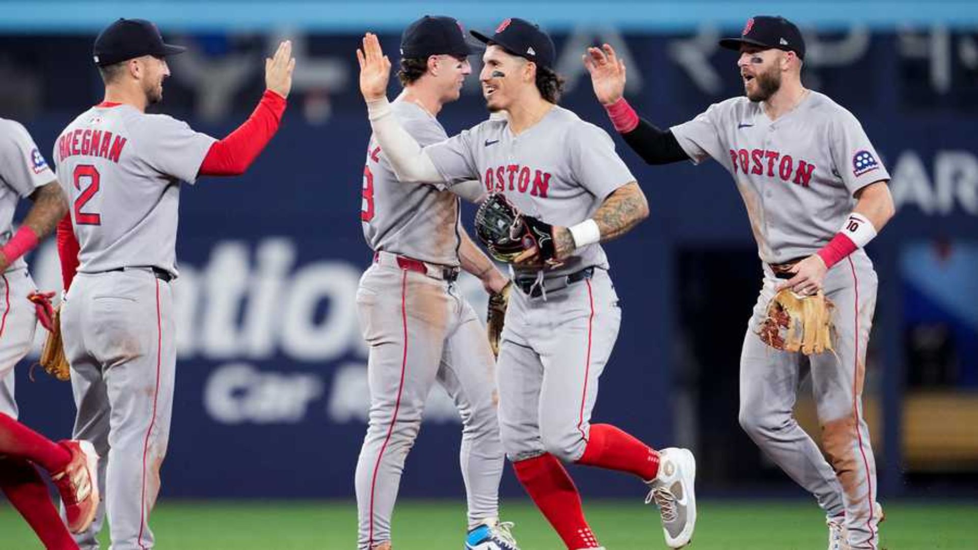 Jugadores de los Boston Red Sox celebrando después de un partido, usando el uniforme gris con el logo de "BOSTON".