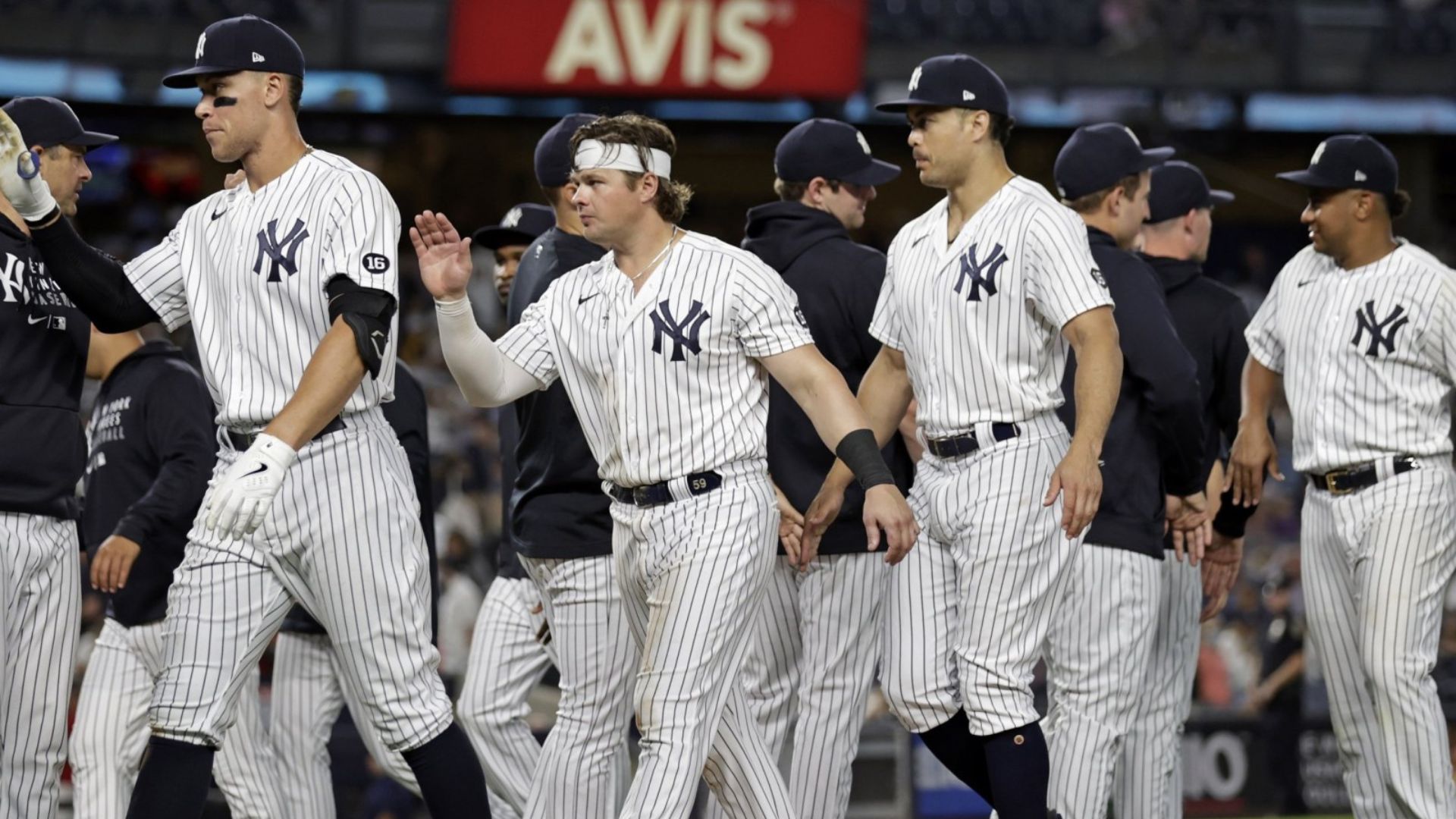 Jugadores de los New York Yankees saludando al final de un partido, usando el uniforme clásico de rayas.
