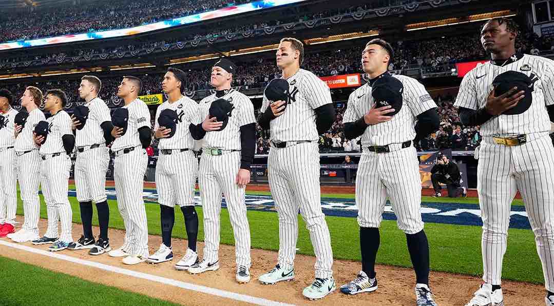 Jugadores de los New York Yankees alineados durante el himno nacional en un estadio lleno.