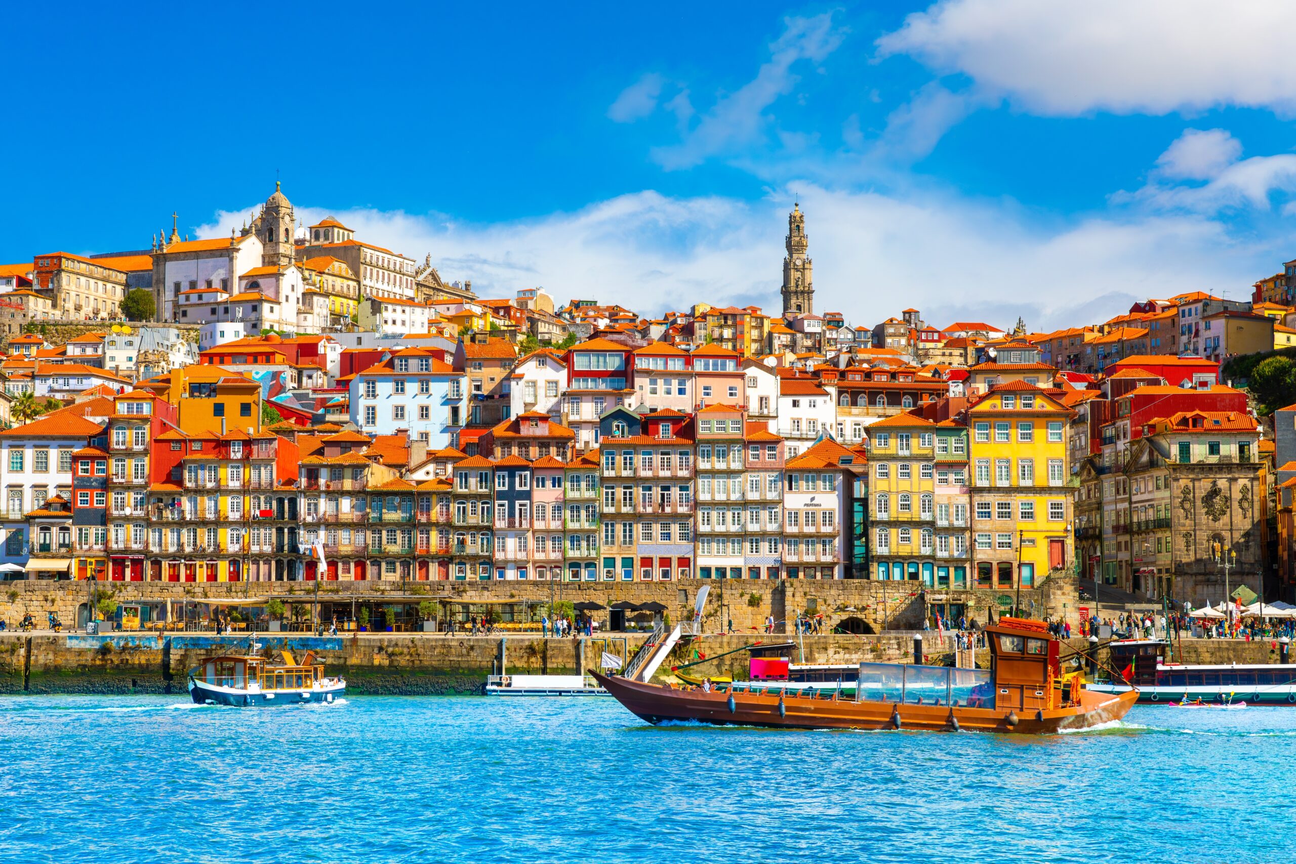 Vista del puerto de Oporto, Portugal, con casas coloridas y un bote navegando por el río Duero.