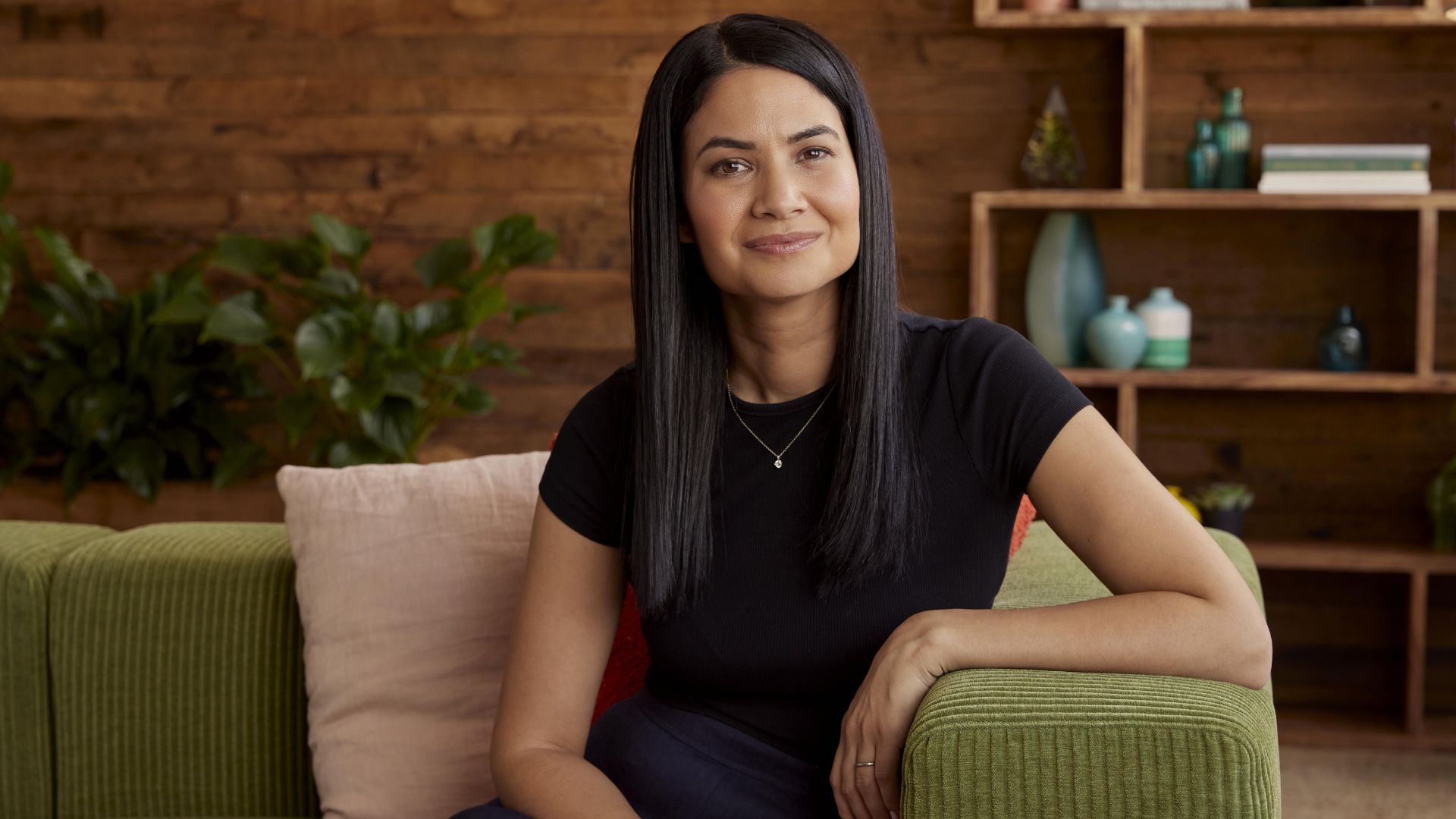 Mujer empresaria sentada en un sofá en una oficina moderna con decoración minimalista.
