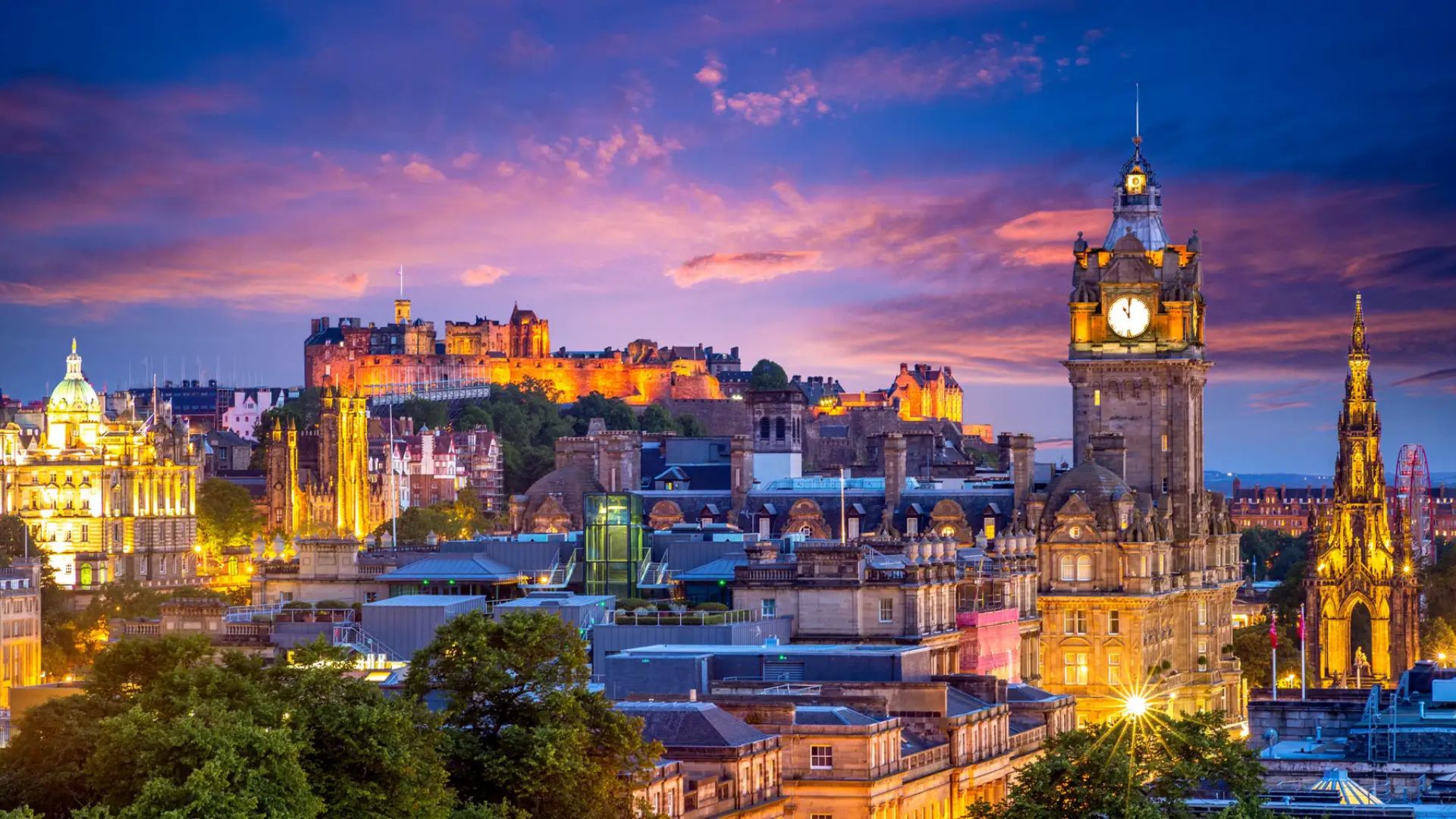 Vista panorámica de Edimburgo al atardecer con el castillo iluminado sobre la colina.