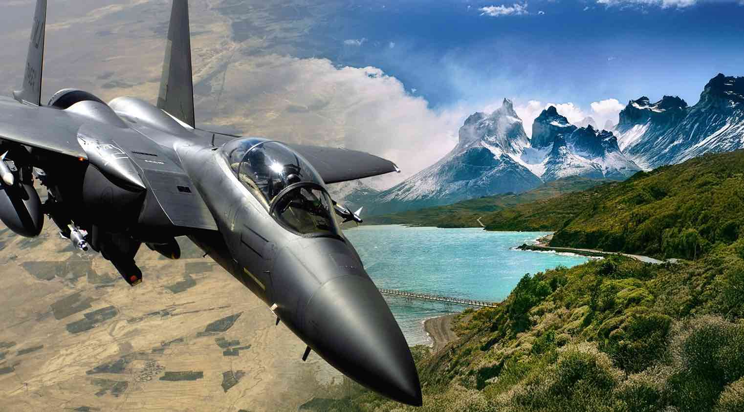 Avión de combate sobrevolando un paisaje montañoso y un lago.