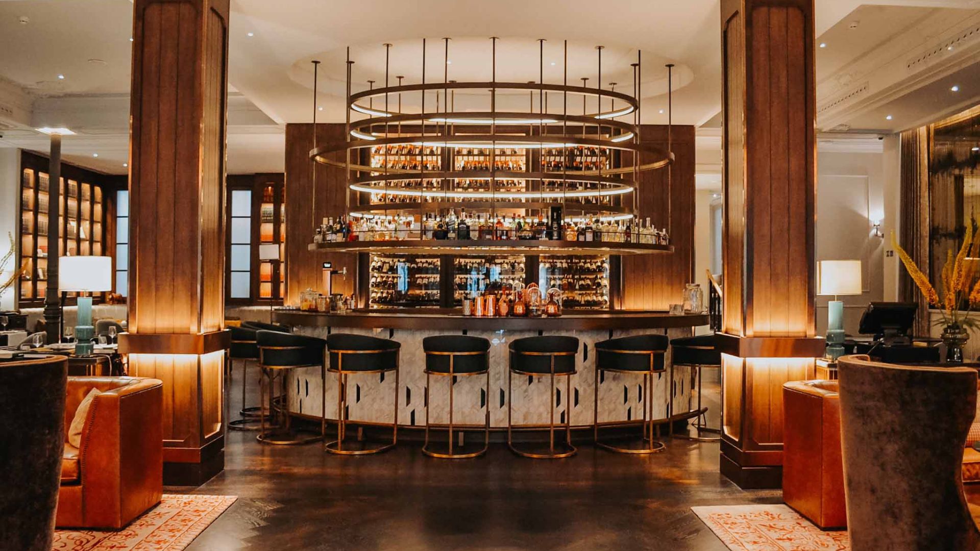 Bar elegante de hotel con iluminación cálida y diseño circular en el centro del salón.