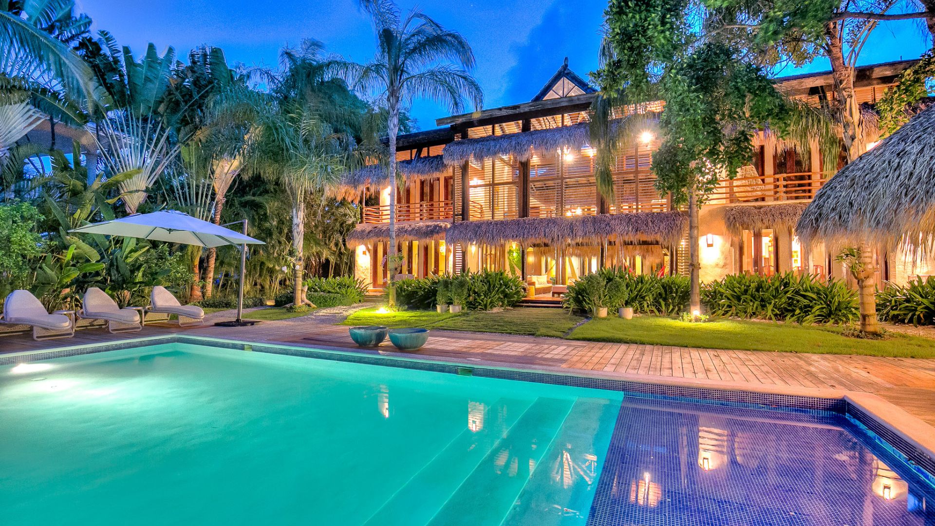 Resort de lujo en Punta Cana con piscina iluminada, palmeras tropicales y arquitectura caribeña.