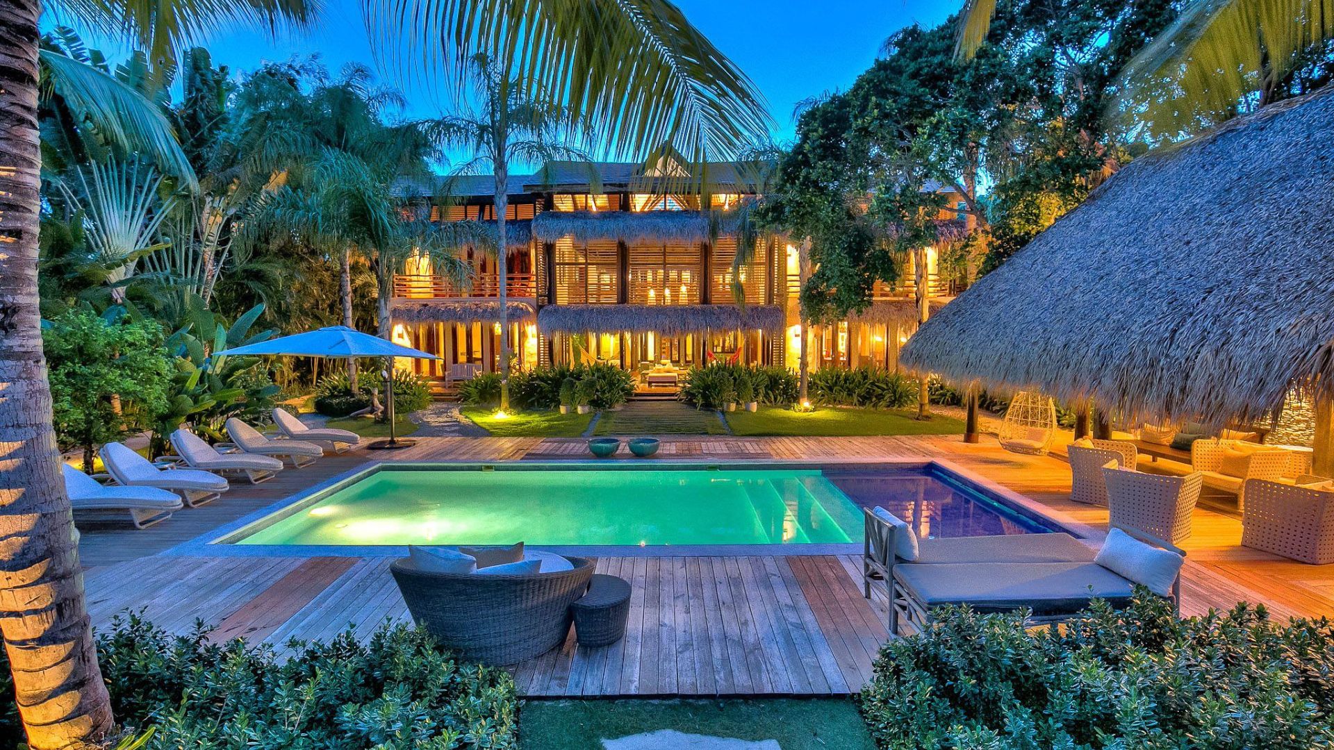 Resort de lujo en Punta Cana con piscina, palmeras tropicales y arquitectura caribeña iluminada al atardecer.