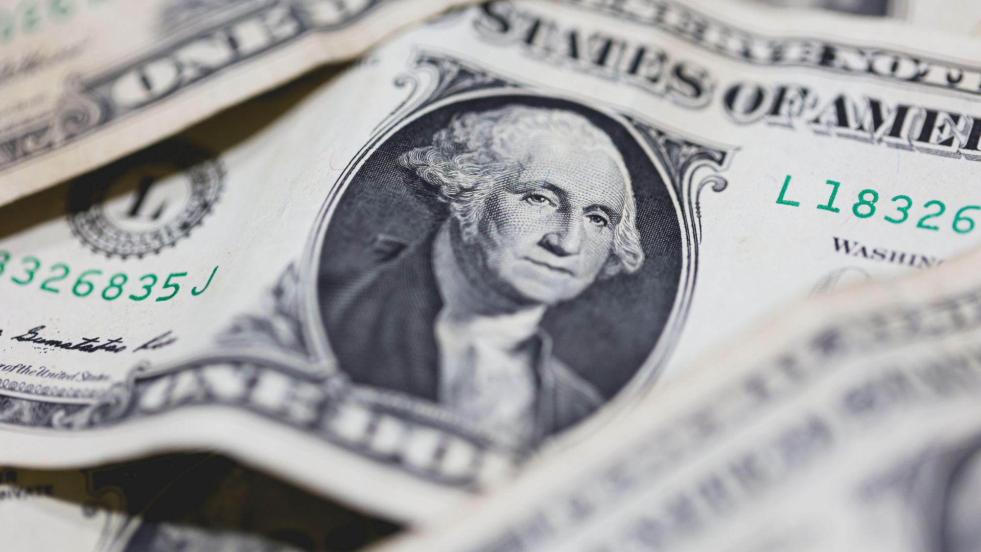 Billetes de 1 dólar estadounidense con un enfoque cercano a la imagen, mostrando detalles de la serie y la figura de George Washington.