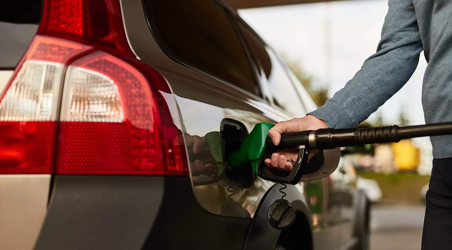 Una persona está llenando el tanque de un automóvil con gasolina en una estación de servicio.