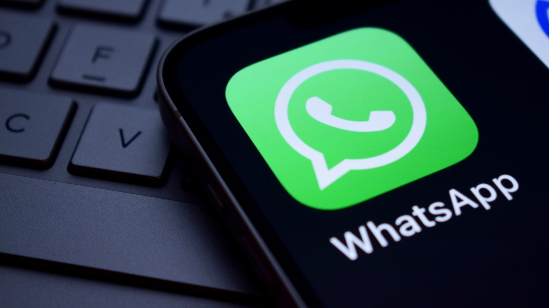Ícono de WhatsApp en la pantalla de un smartphone sobre un teclado.